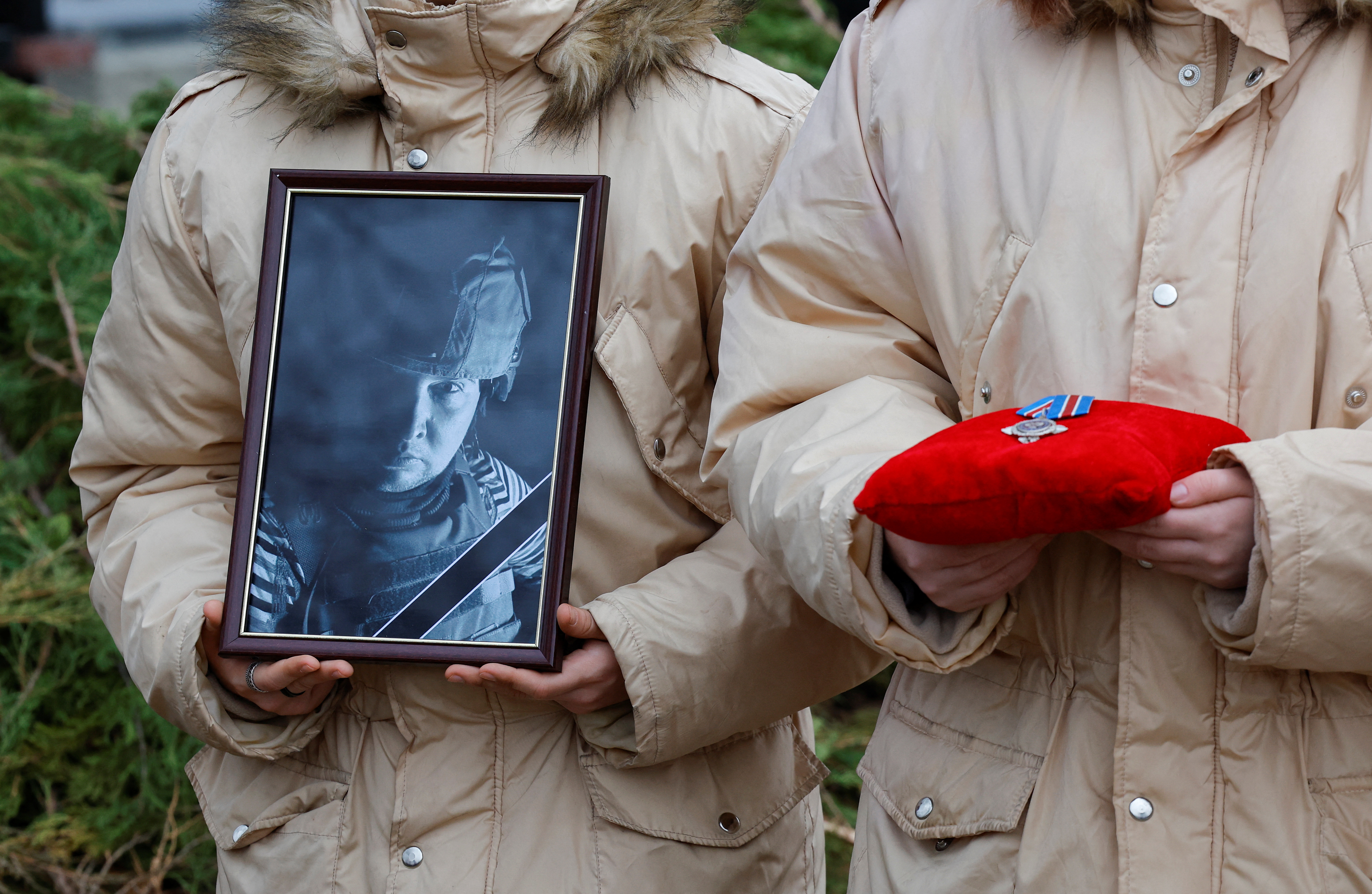 A participant holds a portrait of Alexander Martemyanov, the Russian media outlet Izvestia's freelance correspondent killed in a drone strike on a highway while travelling by car from Horlivka to Donetsk, during a funeral at the Alley of Heroes in the course of Russia-Ukraine conflict in Donetsk, Russian-controlled Ukraine, January 8, 2025. REUTERS/Alexander Ermochenko