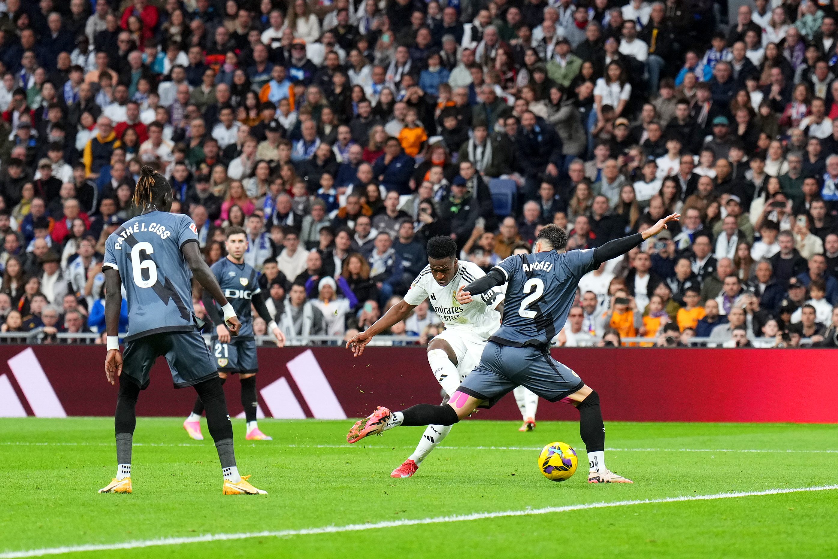Real Madrid’s Vinicius Junior shoots through the legs of Andrei Ratiu of Rayo Vallecano to score his team’s second goal at the Santiago Bernabeu Stadium on March 9, 2025, in Madrid, Spain