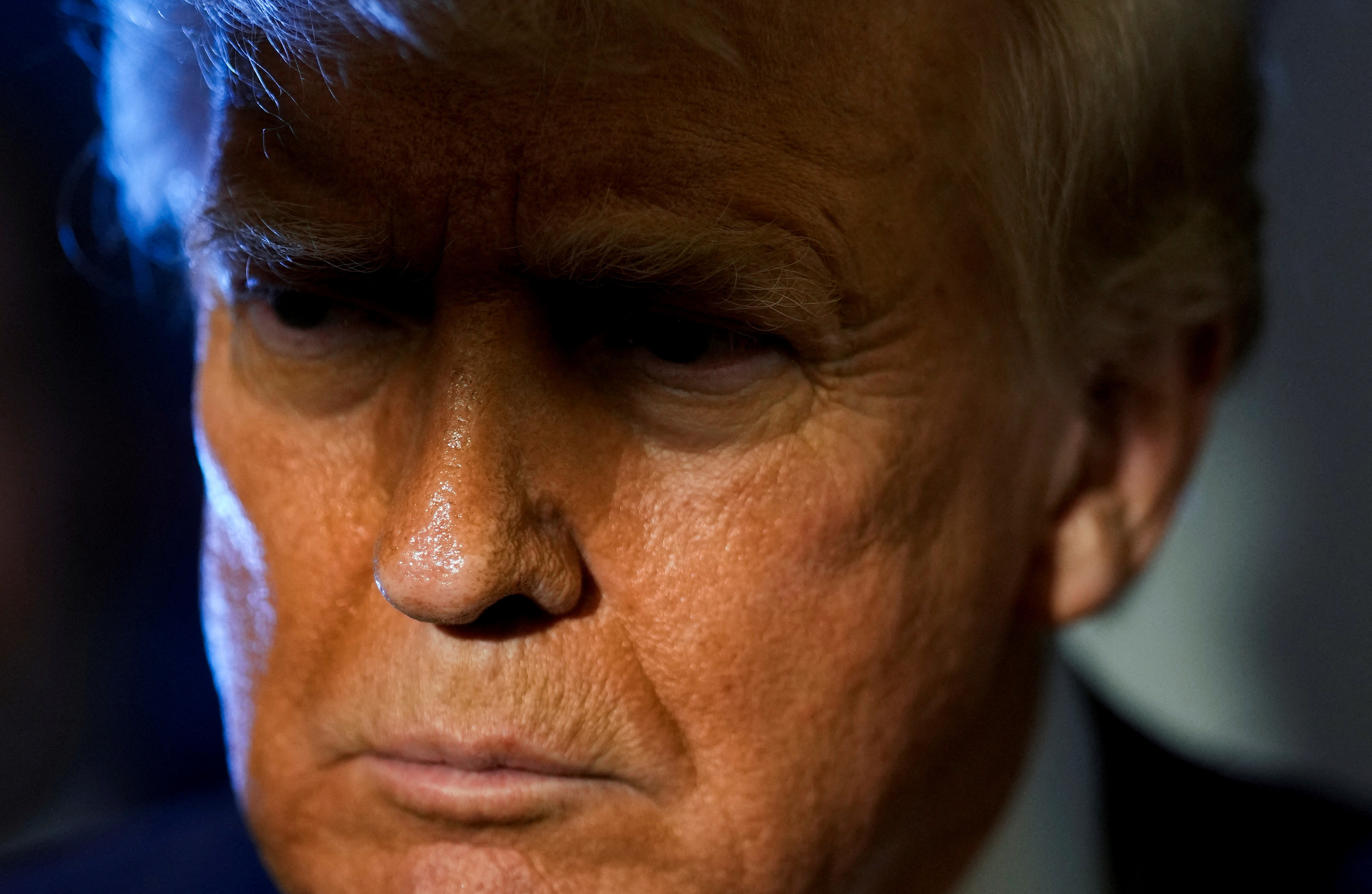 Donald Trump, with the top part of his face in shadow