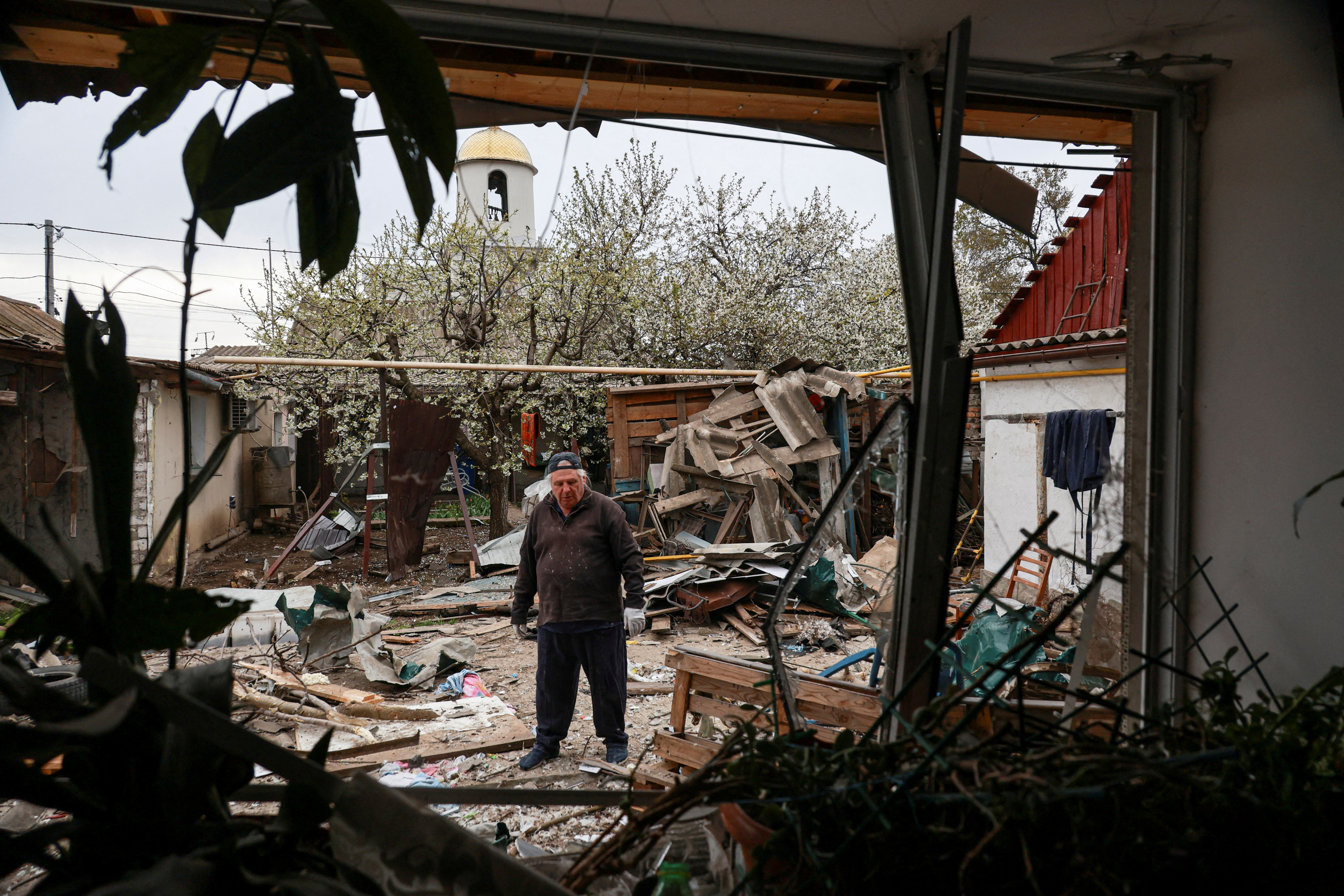 A resident stands on a backyard of his house damaged during a Russian drone strike, amid Russia's attack on Ukraine, in Odesa, Ukraine April 16, 2025. REUTERS/Nina Liashonok TPX IMAGES OF THE DAY