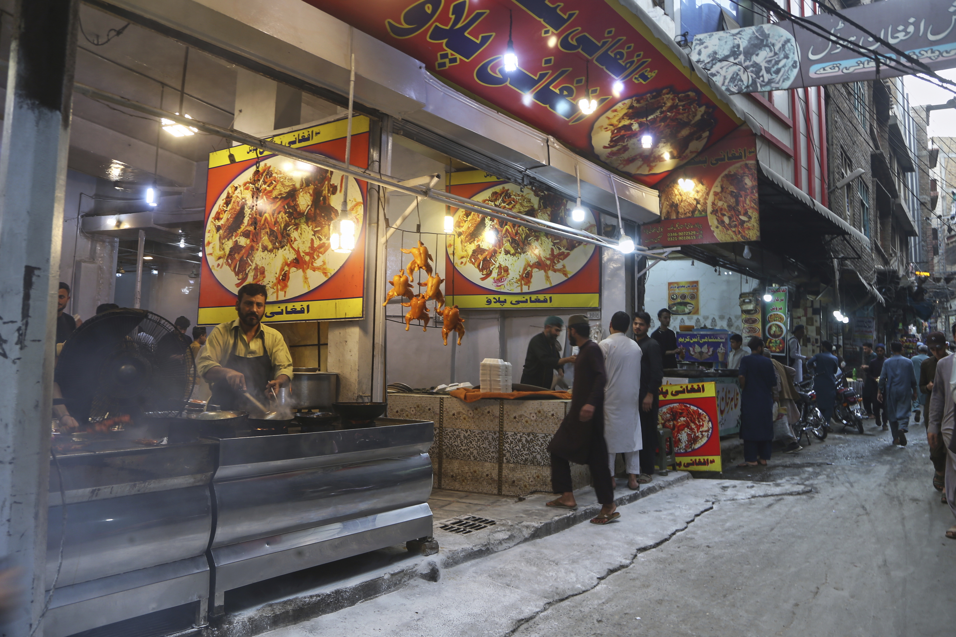 Afghan nationals work in an Afghan restaurant at a market in Peshawar