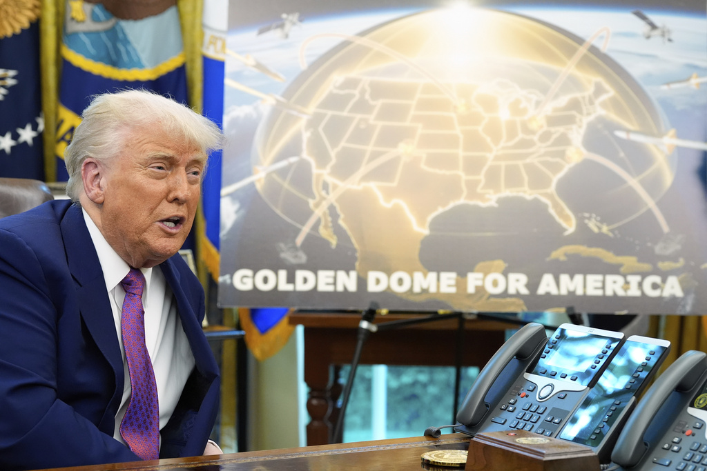 Trump speaks next to a sign saying "Golden dome for America".