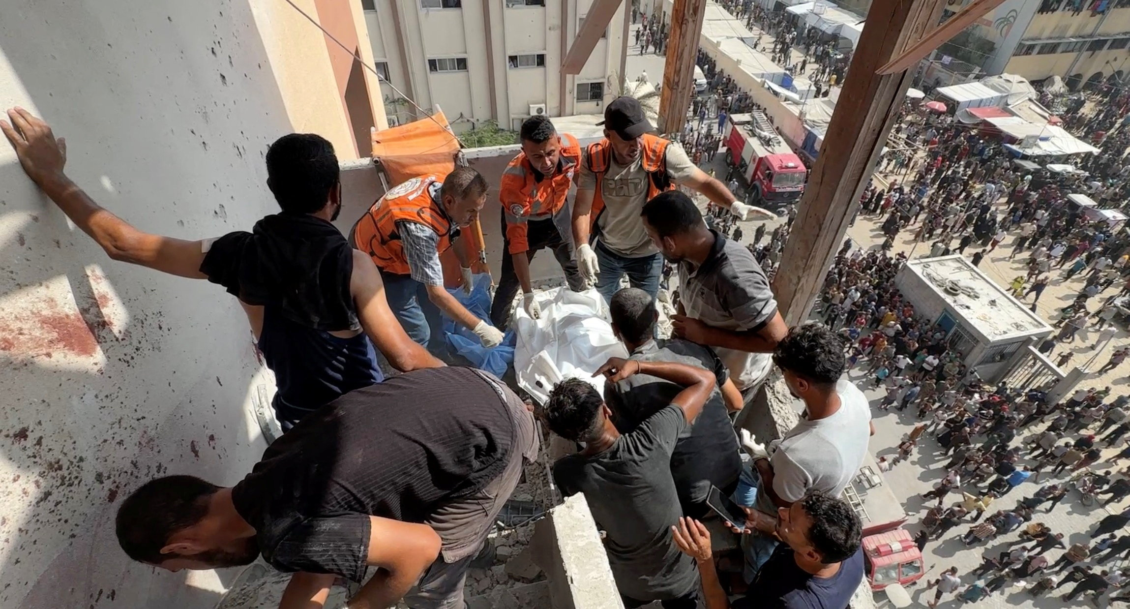 People and rescuers work to recover the body of Palestinian cameraman Hussam al-Masri, who was a contractor for Reuters, after he was killed along with other journalists and people in Israeli strikes on Nasser hospital, in Khan Younis in the southern Gaza Strip, in this still image taken from a video shot by Reuters contractor Hatem Khaled, who was wounded shortly afterwards in another strike while he was filming the site, August 25, 2025. REUTERS/Hatem Khaled TPX IMAGES OF THE DAY
