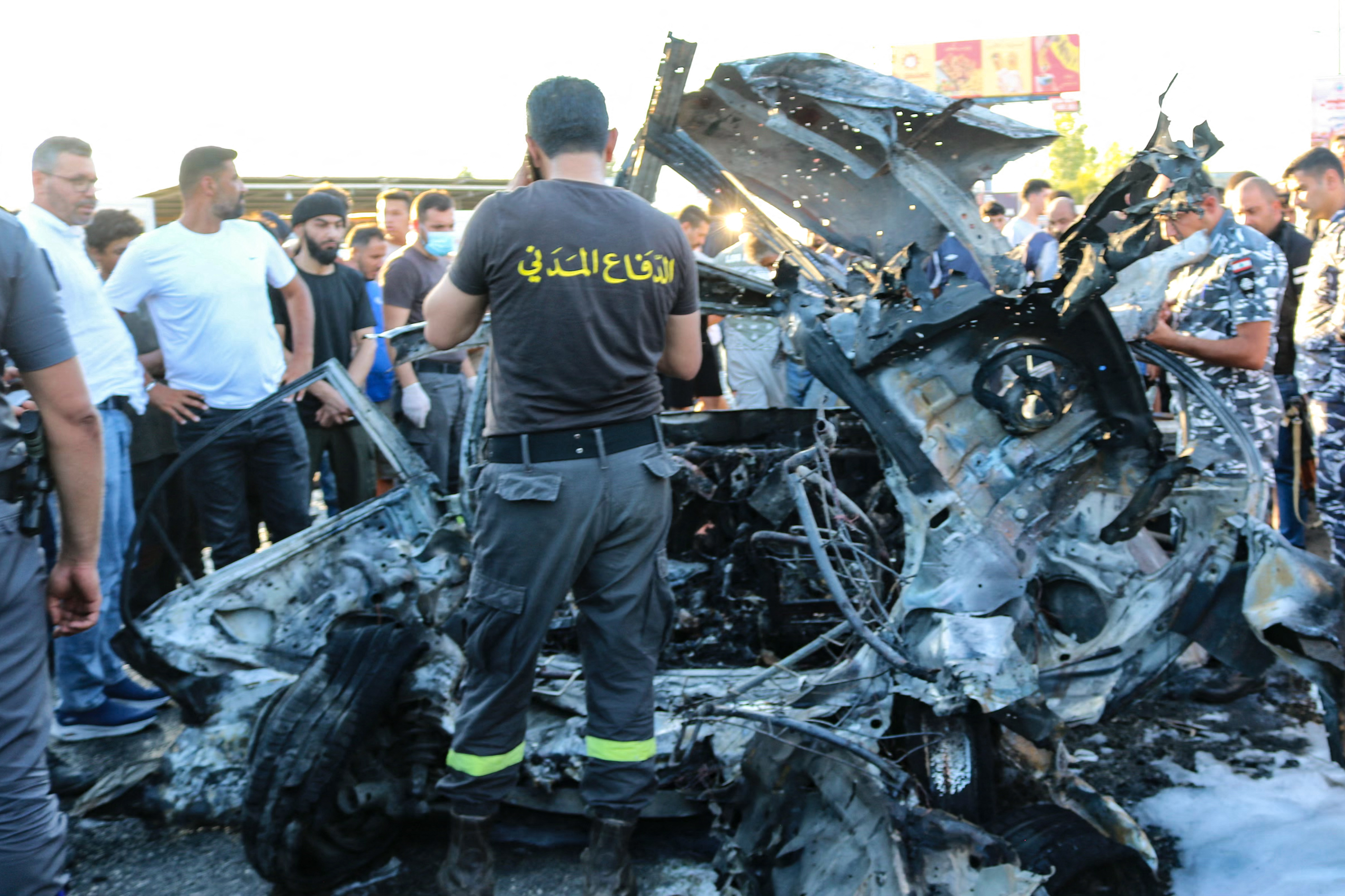 Members of the Lebanese police and civil defence check a car after it was hit by a reported Israeli strike in the Masnaa area in eastern Lebanon on August 7, 2025.