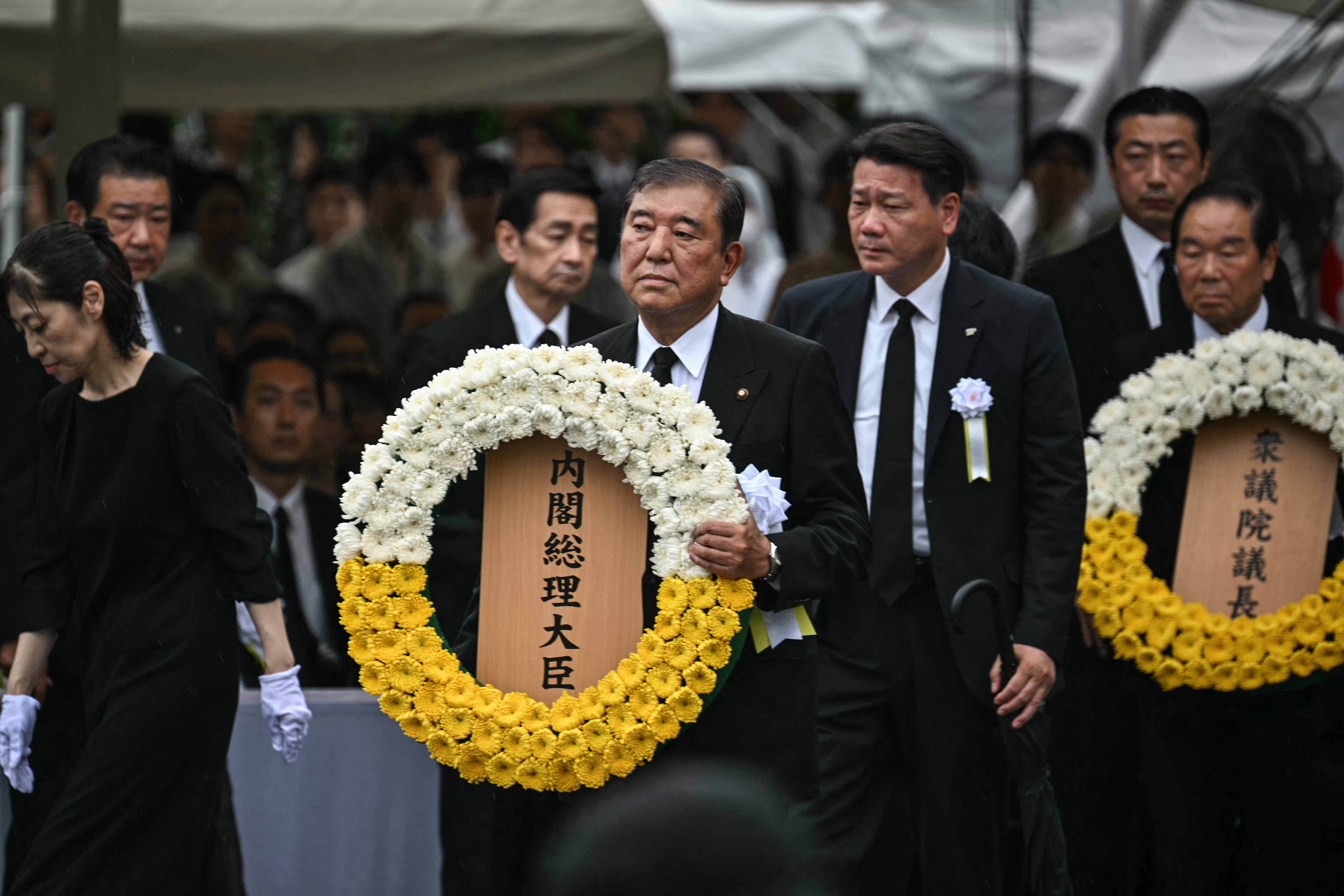 Japan's Prime Minister Shigeru Ishiba (C) prepares to lay a wreath during the annual memorial ceremony for the victims at the Peace Park in Nagasaki on August 9, 2025, to mark the 80th anniversary of the atomic bombing during WWII. (Photo by Philip FONG / AFP)
