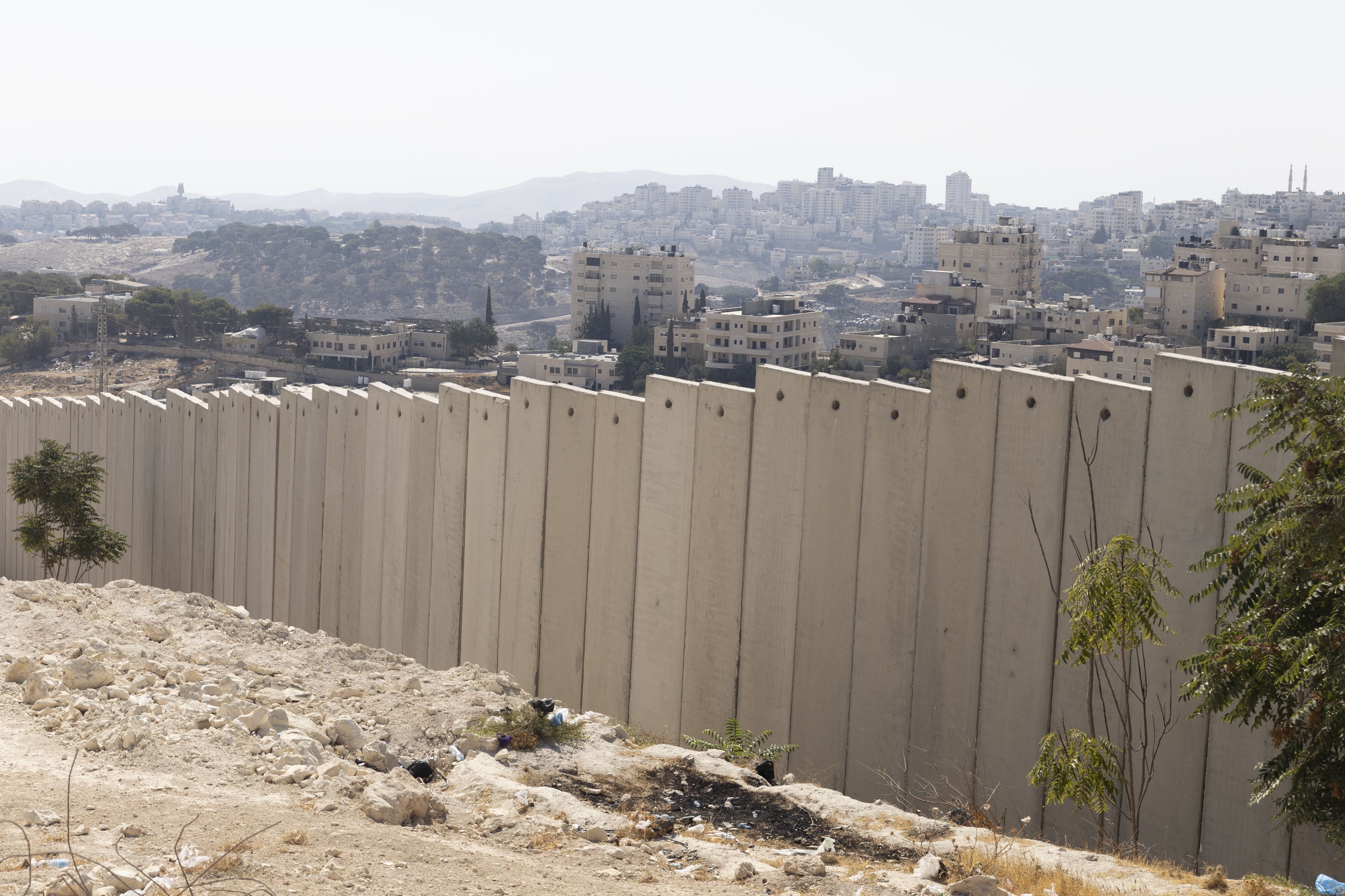 UNSPECIFIED, ISRAEL - AUGUST 22: A view over the separation wall, the Arab village of Al-Eizariya, and The Jewish city of M'aale Adomim, near where the Israeli government plans to build a new neighborhood as part of E1 settlement project on August 22, 2025 in near Jerusalem, Israel. On Wednesday Israel approved plans put forward by far-right Finance Minister Bezalel Smotrich that would see a new Israeli settlement of 3,400 homes built east of Jerusalem in the E1 zone, effectively bisecting much of the occupied West Bank. Until now construction in the area has been prohibited for two decades, and is considered illegal under international law. The move has been condemned by the international community, with critics accusing Israel of sabotaging any prospect of a future two-state solution. (Photo by Amir Levy/Getty Images)