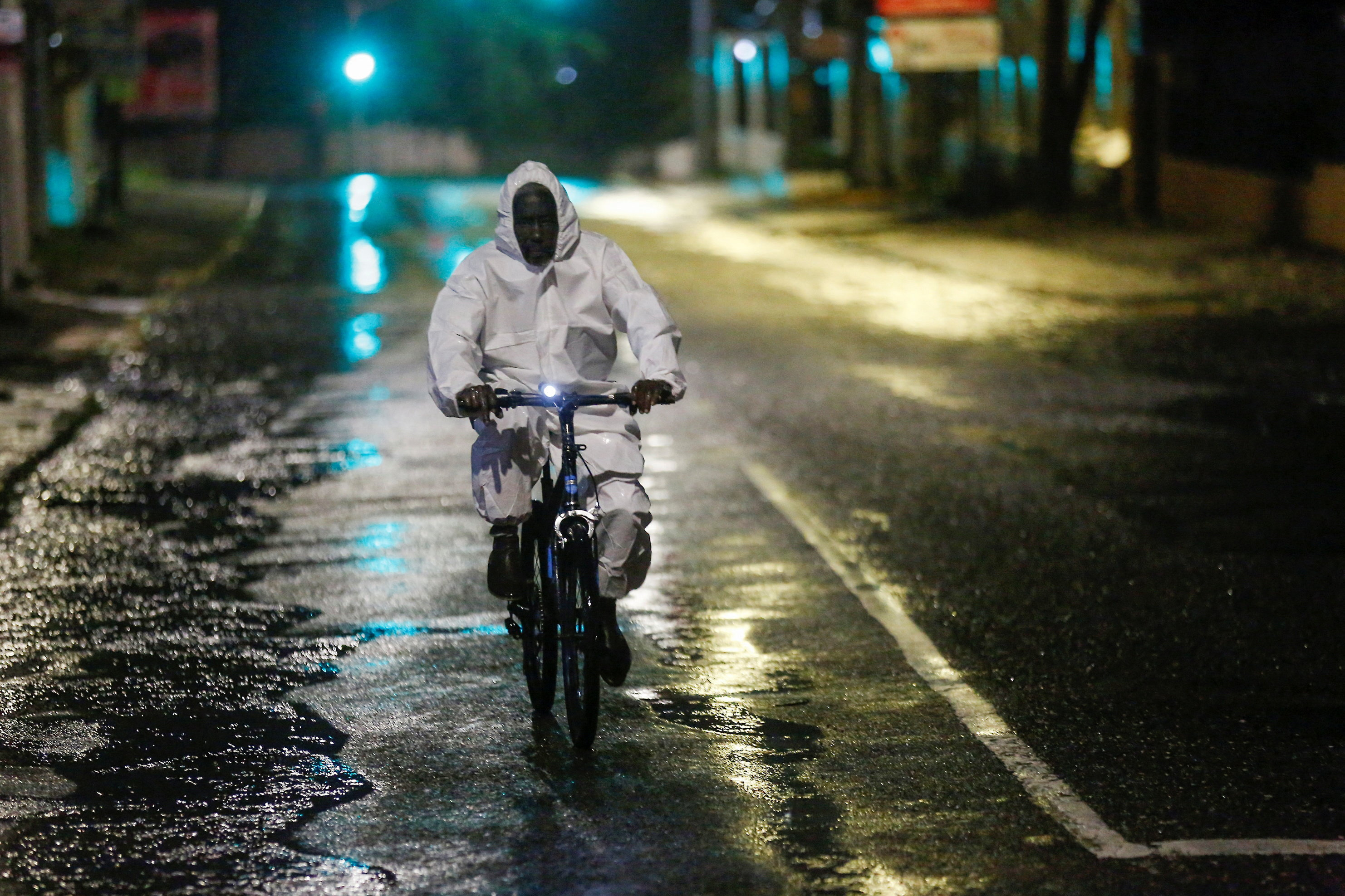 A man wearing a protective suit cycles on a street, as Hurricane Melissa approaches, in Kingston, Jamaica, October 27, 2025.