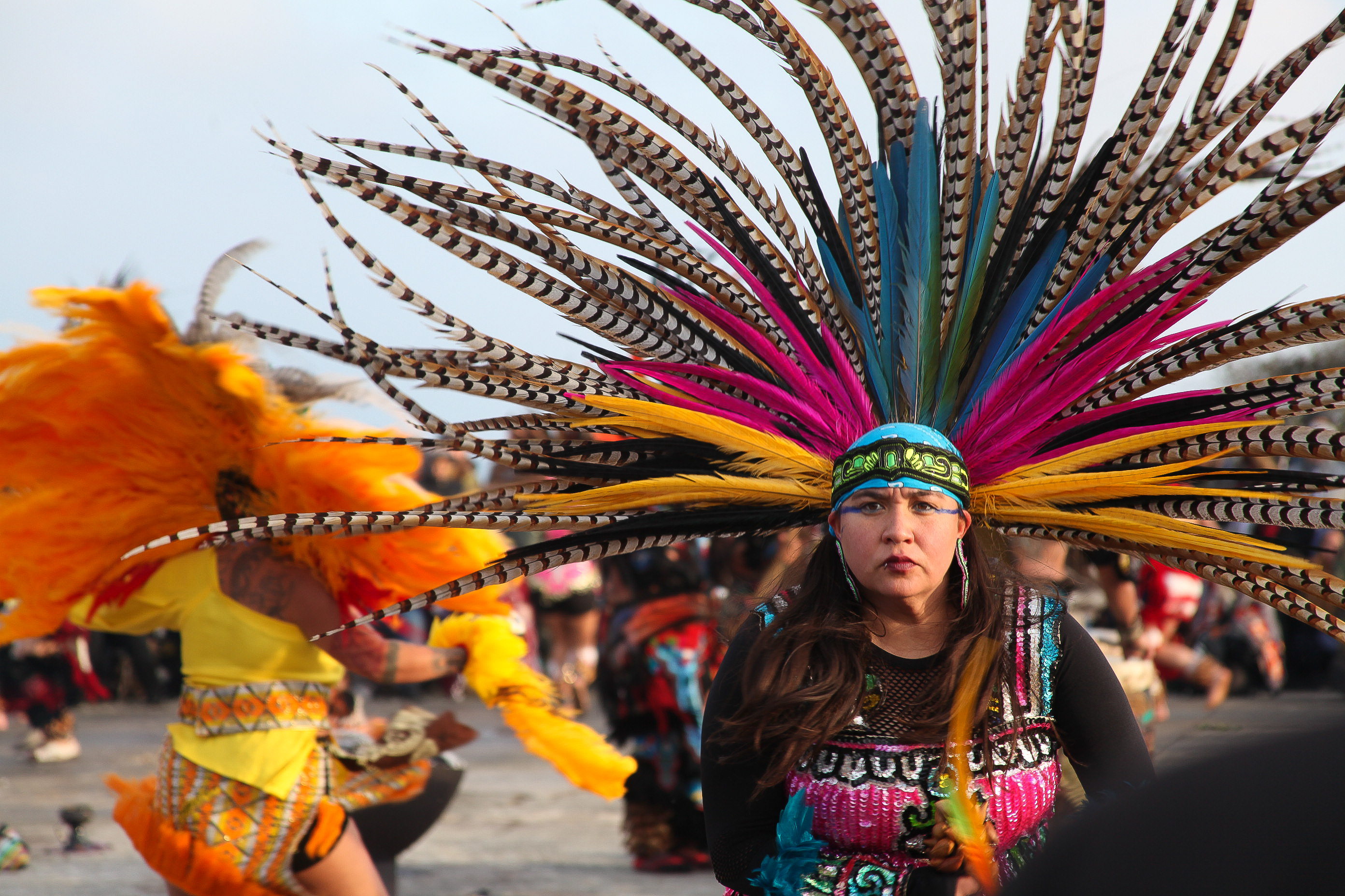 An Indigenous dancer with a large feather headdress dances at a sunrise gathering on Alcatraz.