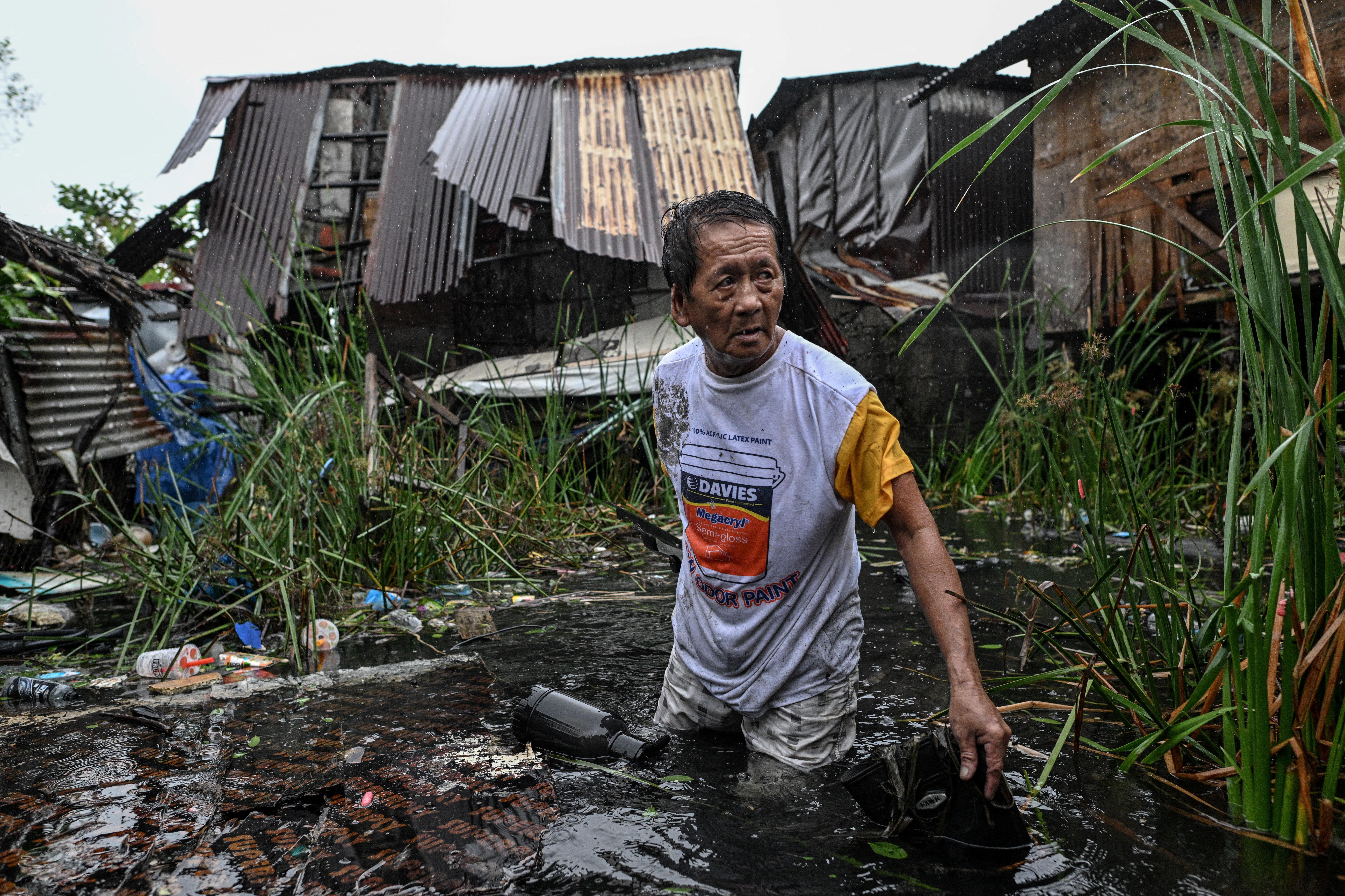 A man wades through the flood as he recovers a roof blown from his house.