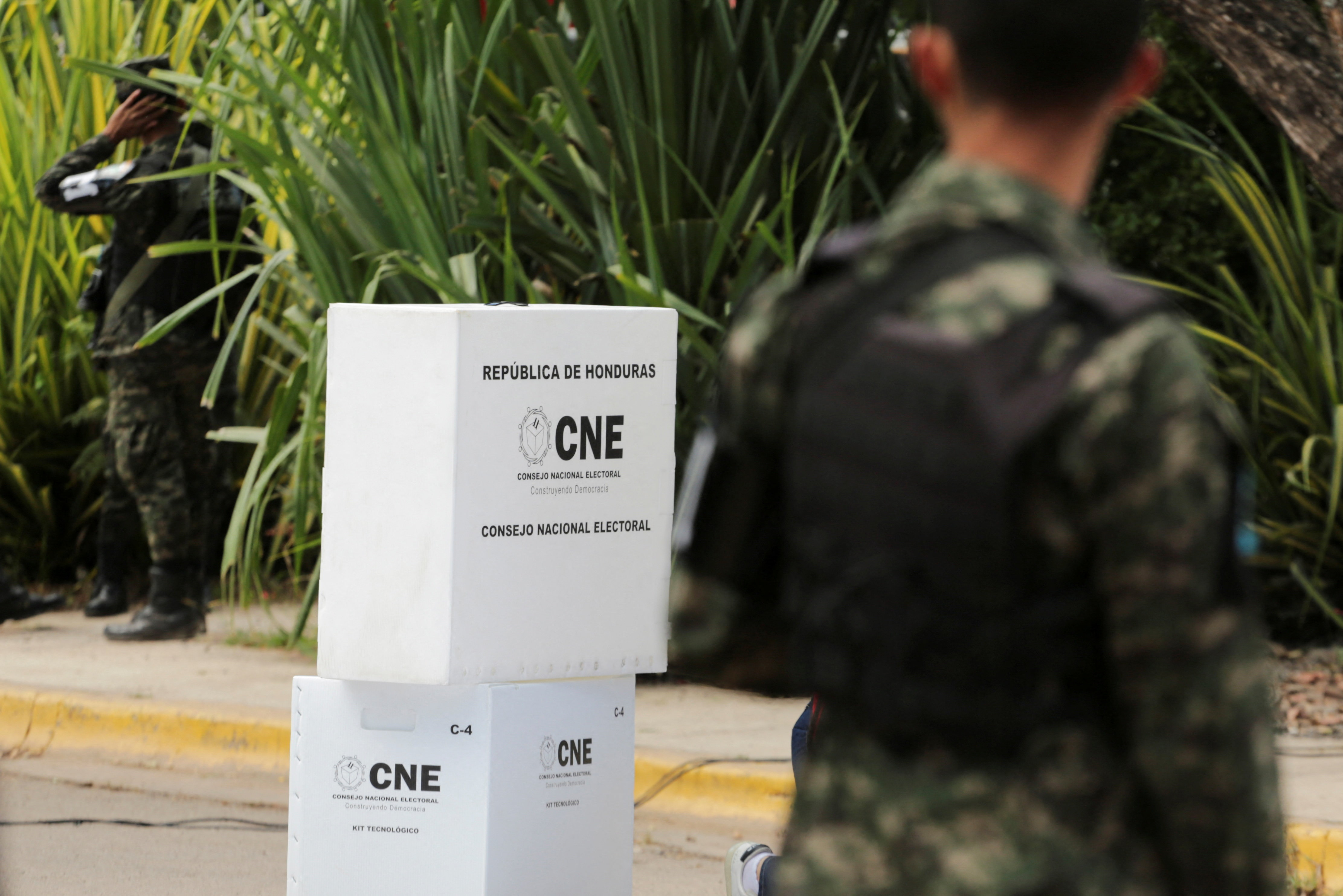 A soldier stands guard over ballot boxes labelled with the acronyme CNE