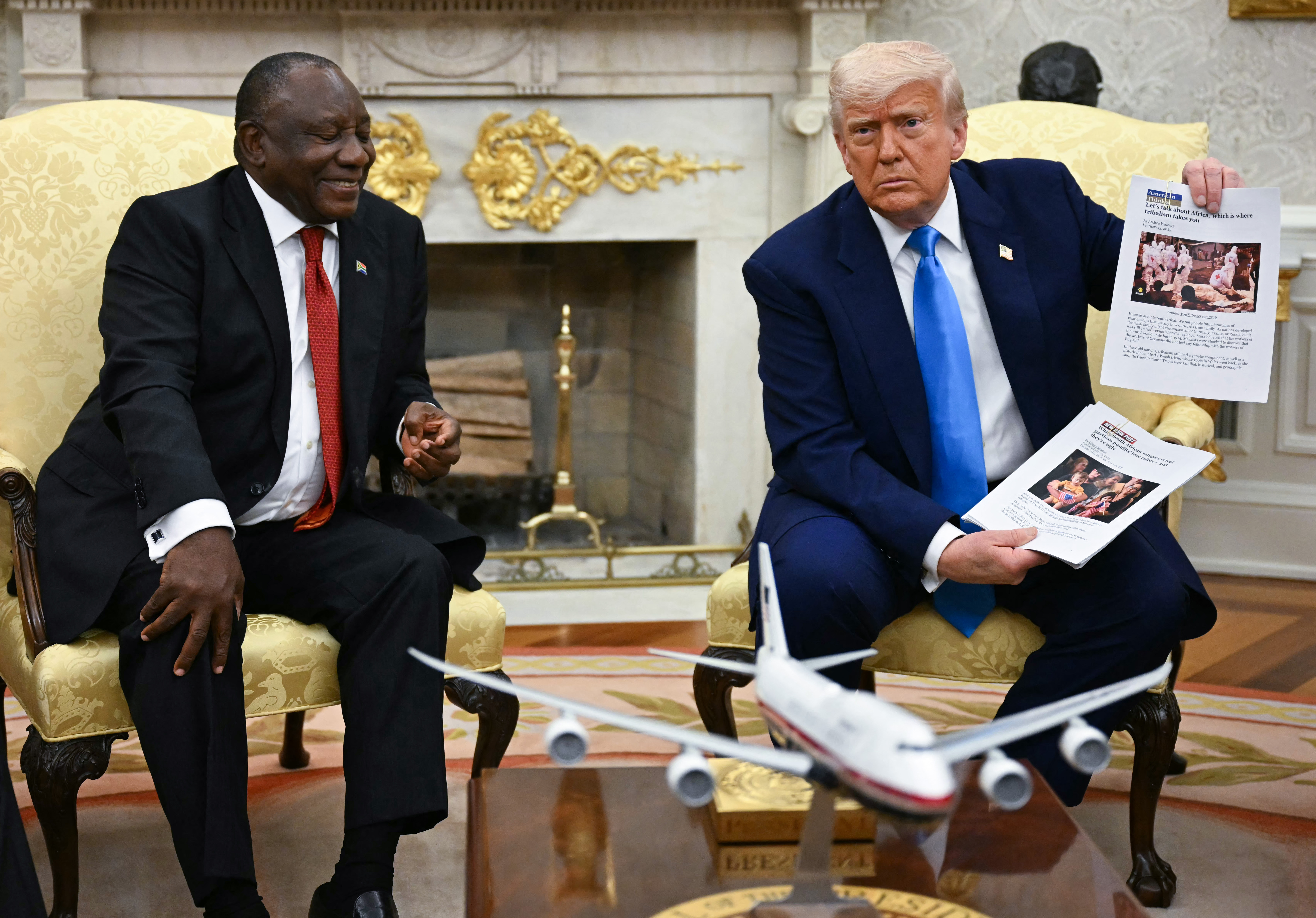 US President Donald Trump shows pictures as he meets with South African President Cyril Ramaphosa in the Oval Office of the White House in Washington, DC, on May 21, 2025. South African President Cyril Ramaphosa meets Donald Trump on Wednesday amid tensions over Washington's resettlement of white Afrikaners that the US president claims are the victims of "genocide." (Photo by Jim WATSON / AFP)