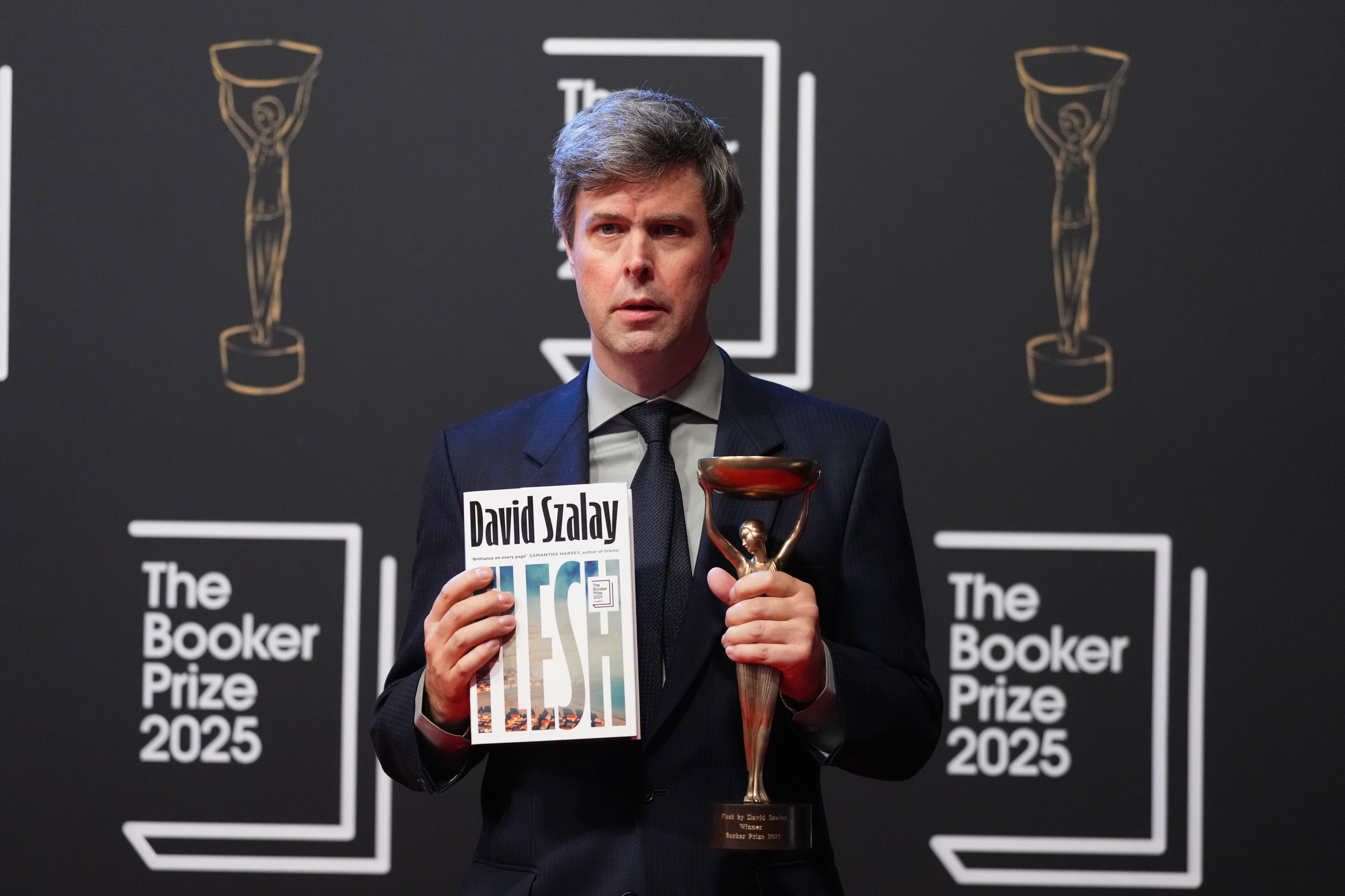 Hungarian-British author David Szalay poses for photographers with the trophy after winning the Booker Prize 2025 for his book 'Flesh' during a ceremony at Old Billingsgate in London, Monday, Nov. 10, 2025. (AP Photo/Kirsty Wigglesworth)