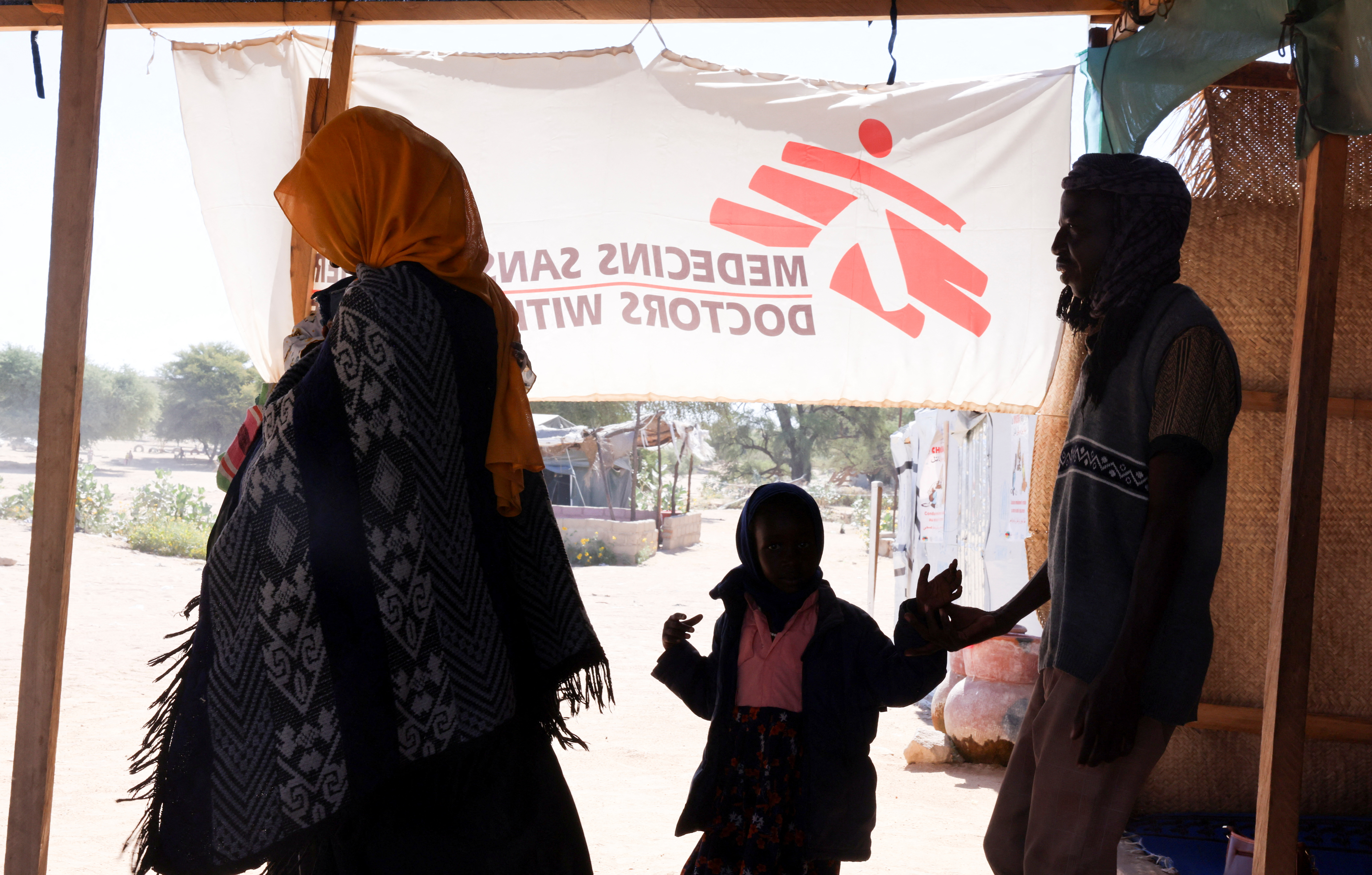 Ibrahim Mohamed Ishaq, 35, a Sudanese refugee father from al-Fashir, walks alongside his wife Fatima Abdul Karim, 25, and their daughters Eman, 5, and Eilaf, 3, for a medical check from members of Medecins Sans Frontieres (MSF) after passing the Tine border post in eastern Chad, as they flee ongoing clashes between the paramilitary Rapid Support Forces (RSF) and the Sudanese army, November 22, 2025. REUTERS/Amr Abdallah Dalsh