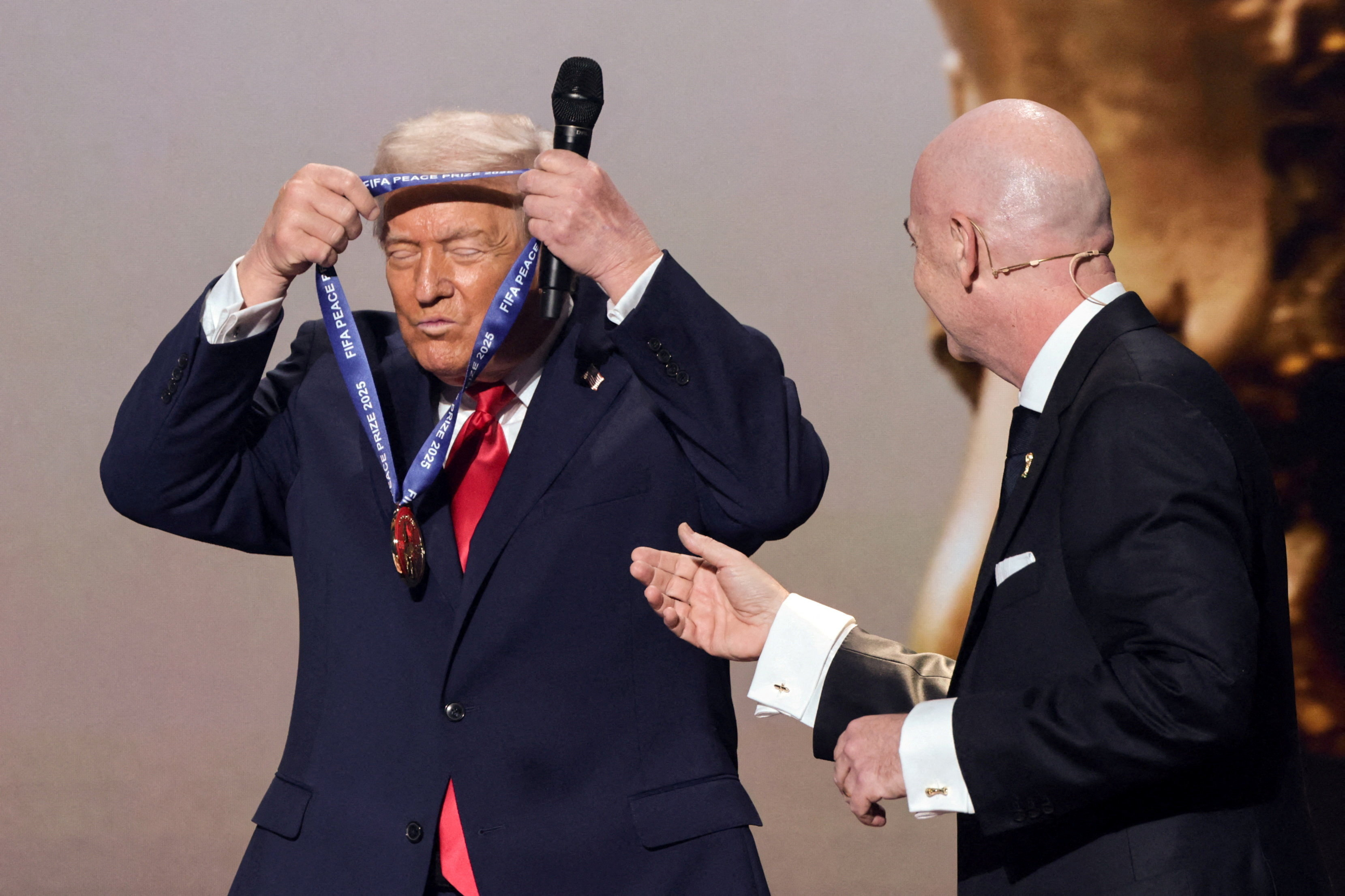 Trump puts a medal over his head as Gianni Infantini watches