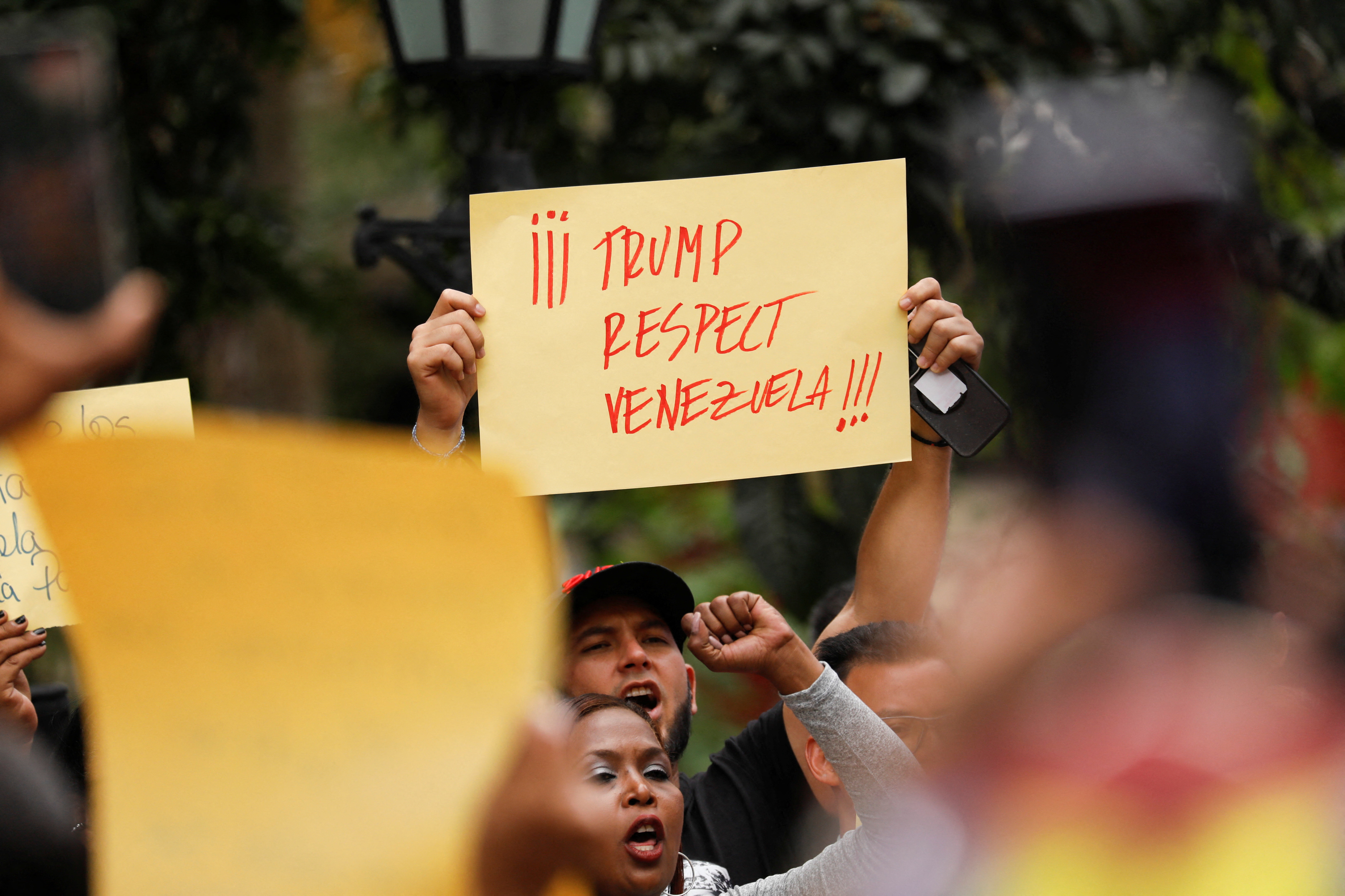 A pro-Maduro protester holds up a sign that reads, "Trump respect Venezuela"