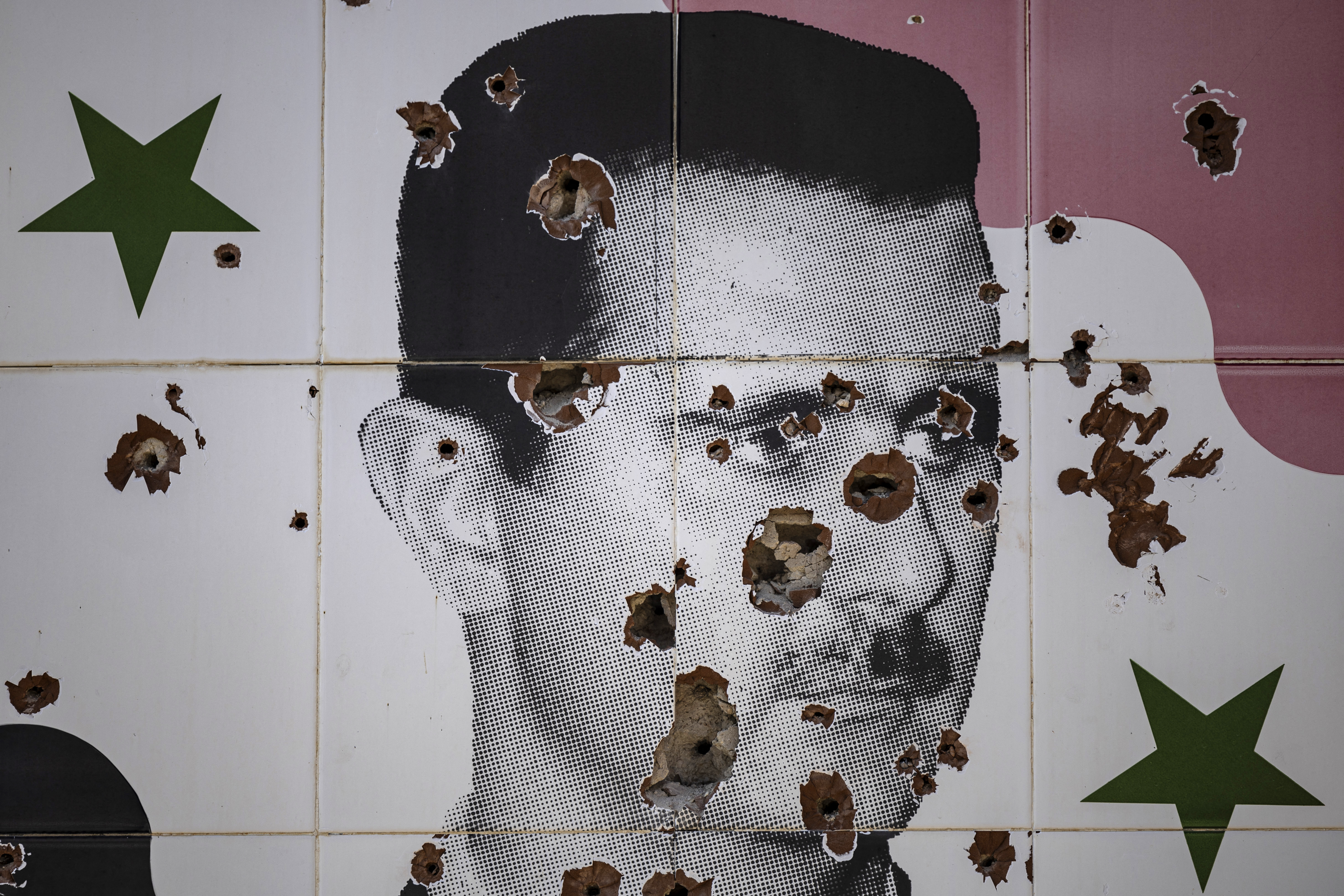 Bullet holes deface a mural depicting the toppled Syrian president Bashar al-Assad in Adra town on the northeastern outskirts of Damascus on December 25, 2024. [Sameer Al-Doumy / AFP]