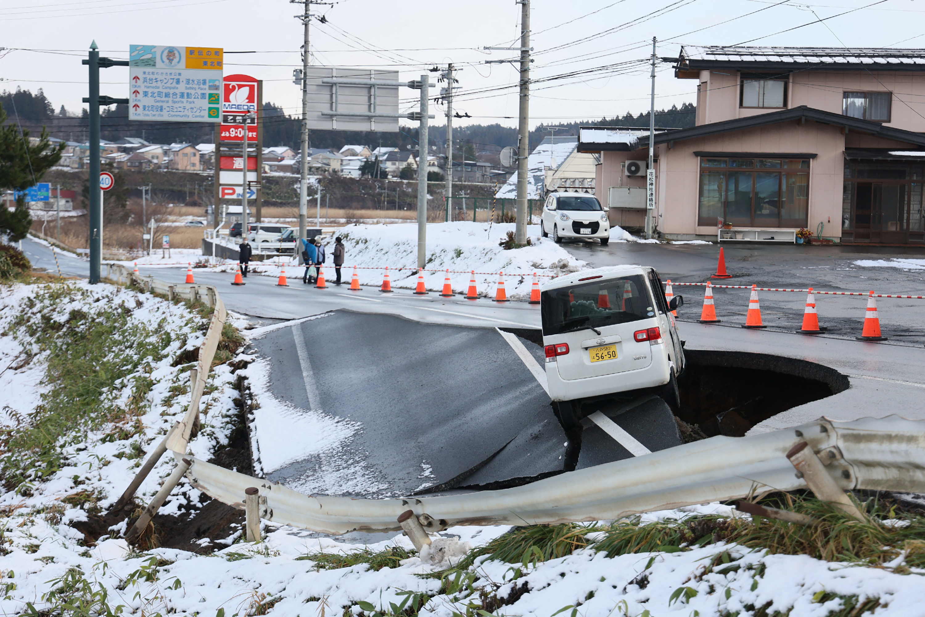 A vehicle rests on the edge of a collapsed road in Tohoku town in Aomori Prefecture on December 9, 2025, following a 7.5 magnitude earthquake off northern Japan. A big quake off northern Japan left at least 30 injured, authorities said on December 9, damaging roads and leaving thousands without power in freezing temperatures. (Photo by JIJI Press / AFP) / Japan OUT / JAPAN OUT / JAPAN OUT