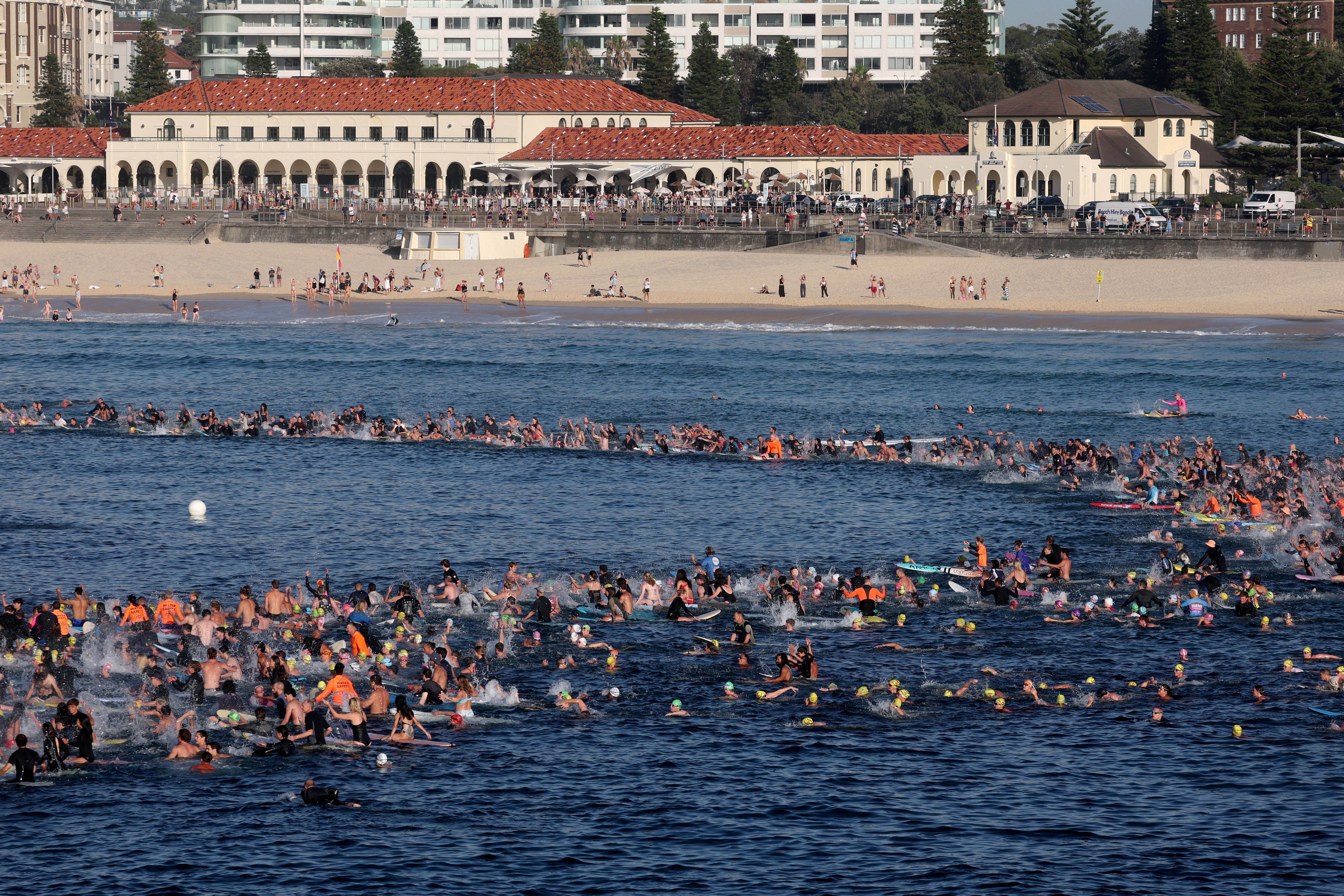 Surfers and swimmers congregate in the surf at Bondi Beach as they participate in a tribute for the victims of Sundays Bondi Beach attack, in Sydney on December 19, 2025. Australia's leaders have agreed to toughen gun laws after attackers killed 15 people at a Jewish festival on Bondi Beach, the worst mass shooting in decades decried as antisemitic "terrorism" by authorities. (Photo by DAVID GRAY / AFP)