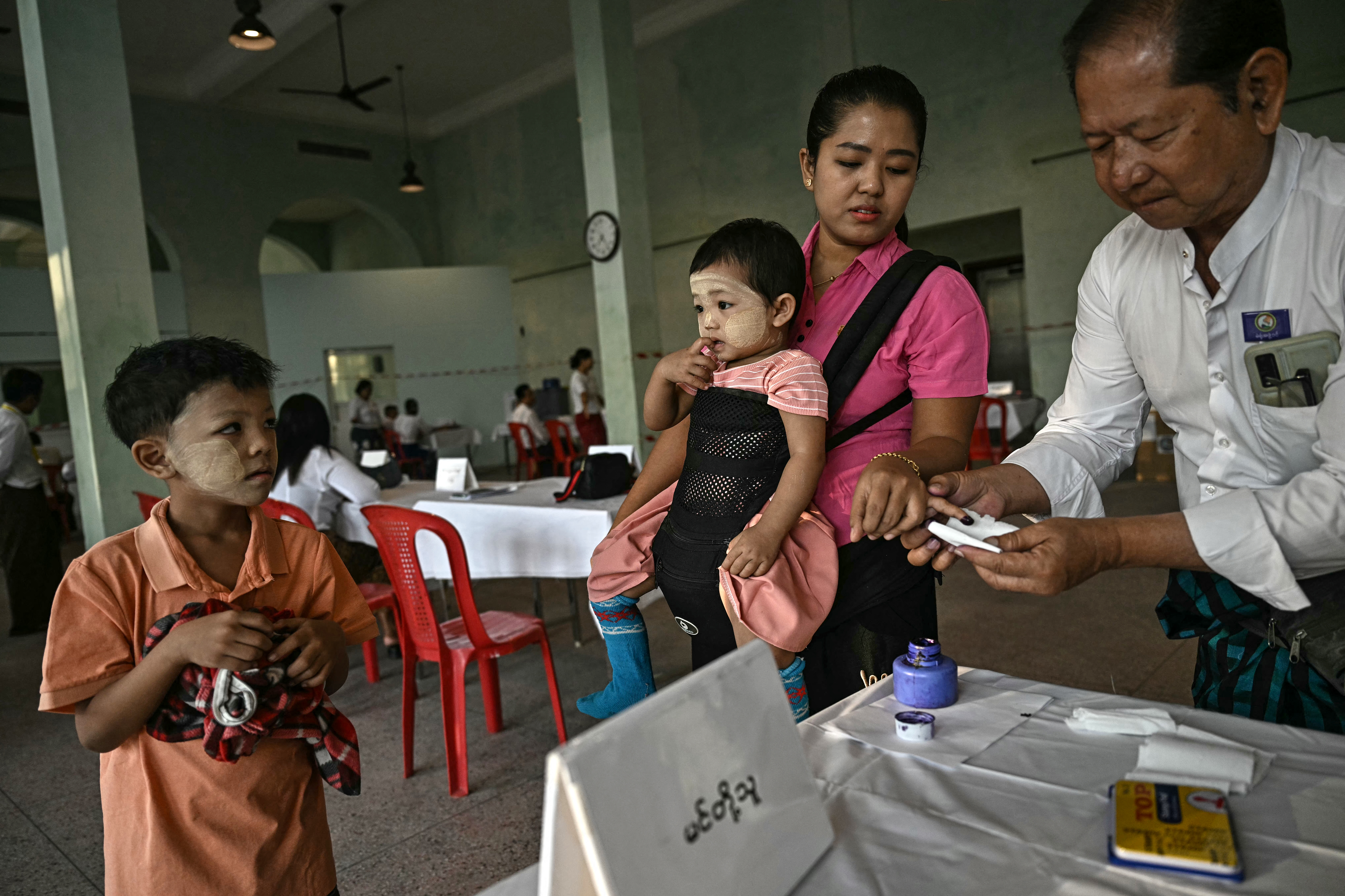 A woman has her finger inked after voting at a polling station in Yangon