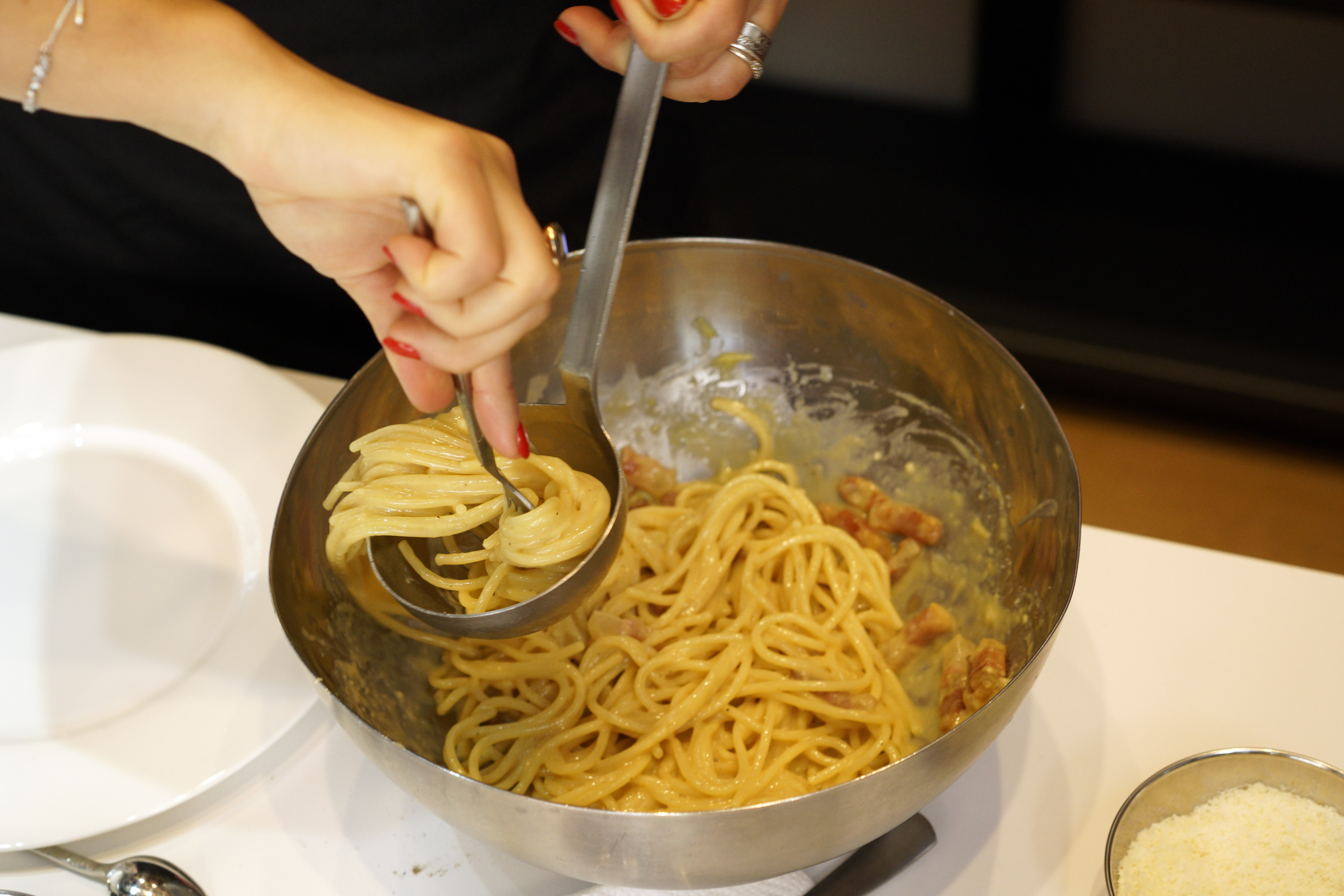 A woman spoons onto a plate some "spaghetti alla Carbonara" during a cooking competition on the eve of the Carbonara Day