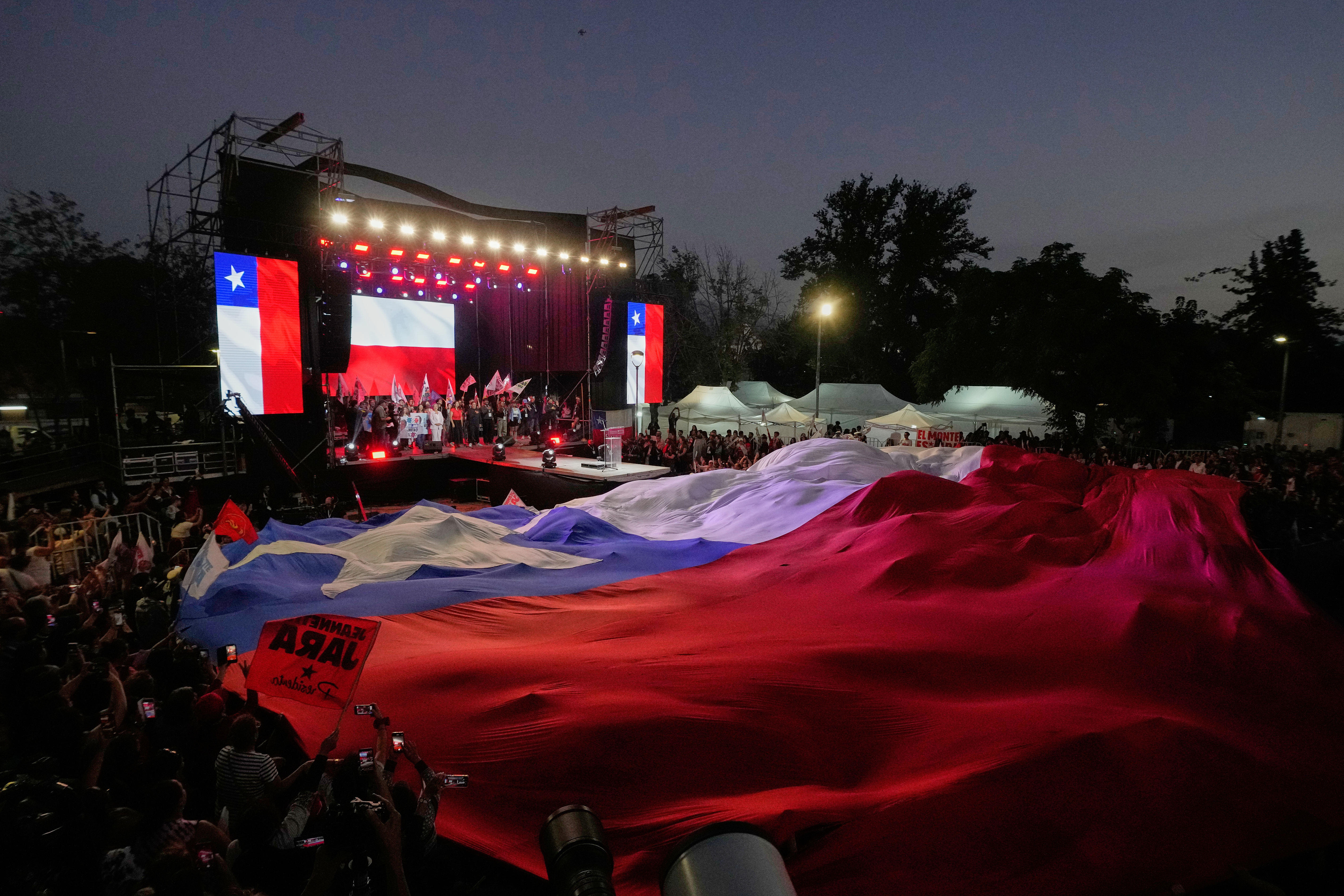 A large Chilean flag unfurls in the audience of a Jeannette Jara rally