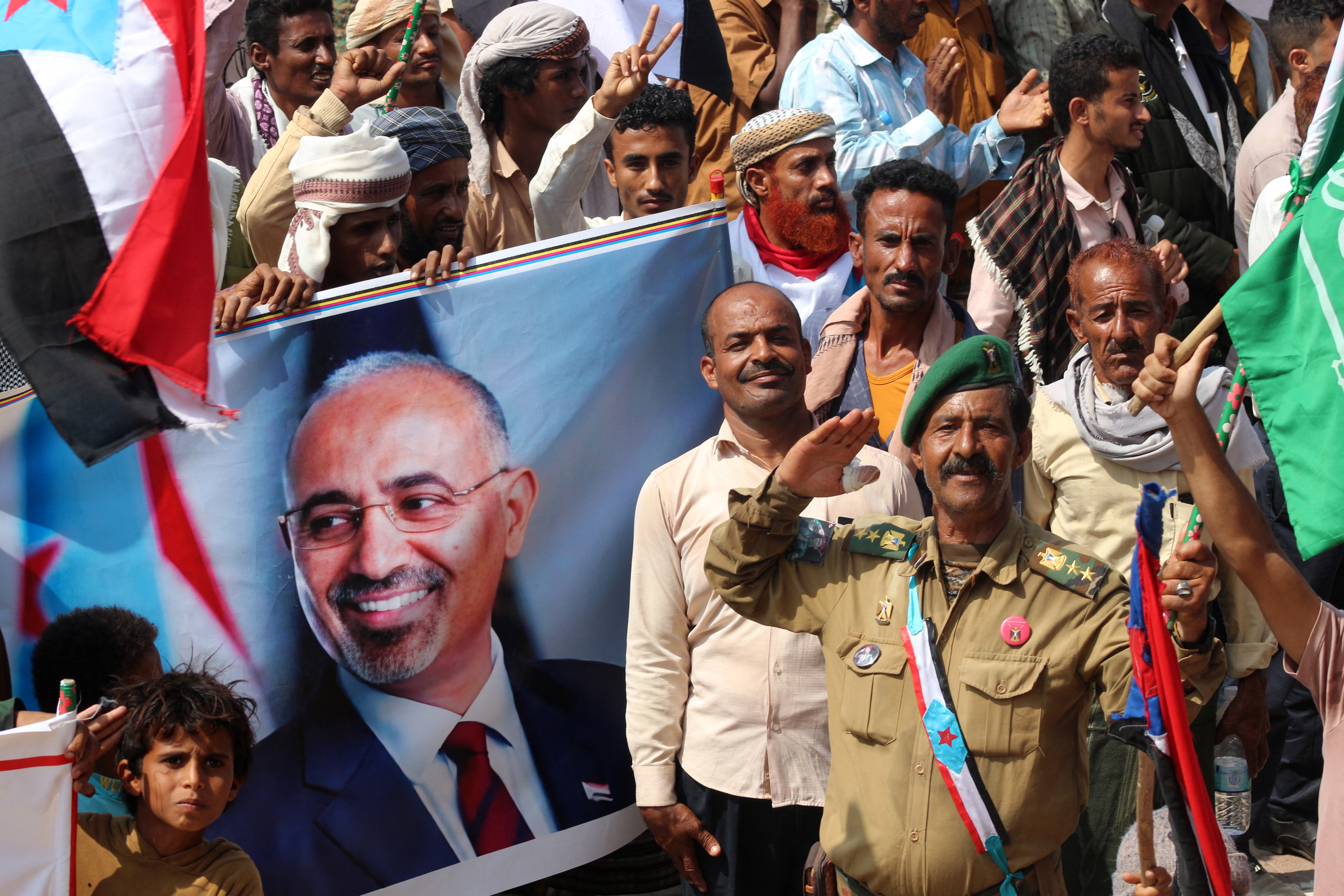 Yemenis members of the Sabahiha tribes of Lahj, who live along the strip between the south and north of the country and who support the UAE-backed Southern Transitional Council (STC), hold an image of the STC leader Aidaros Alzubidi as they wave the old South Yemen flag, during a rally in Khormaksar Square, in the coastal port city of Aden, the temporary capital of the Republic of Yemen on December 14, 2025.