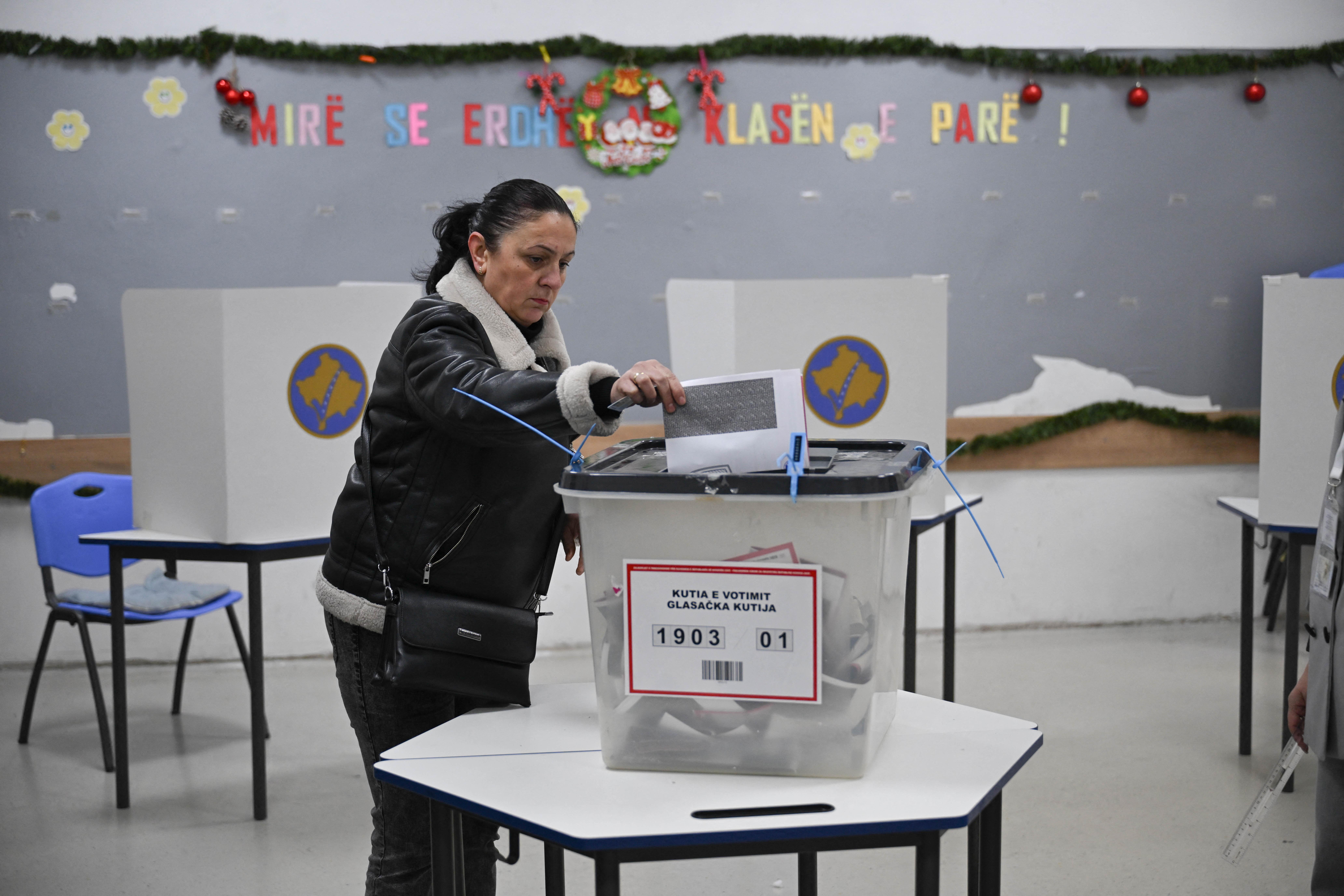 A woman casts her vote at a polling station in Pristina on December 28, 2025.