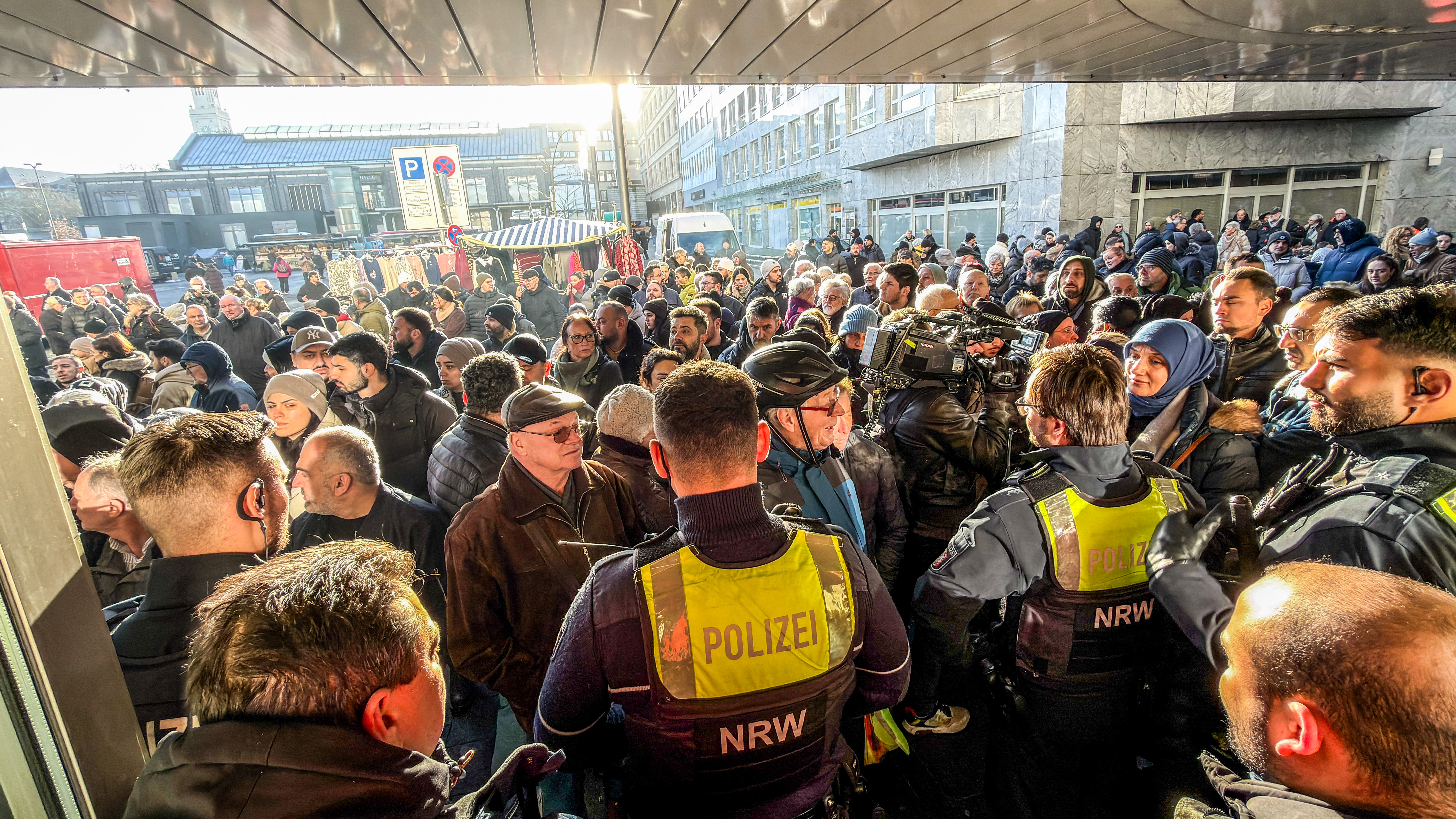 Policemen and concerned bank customers stand in front of a branch of the Sparkasse bank in Gelsenkirchen, western Germany, on December 30, 2025, after the bank was robbed.