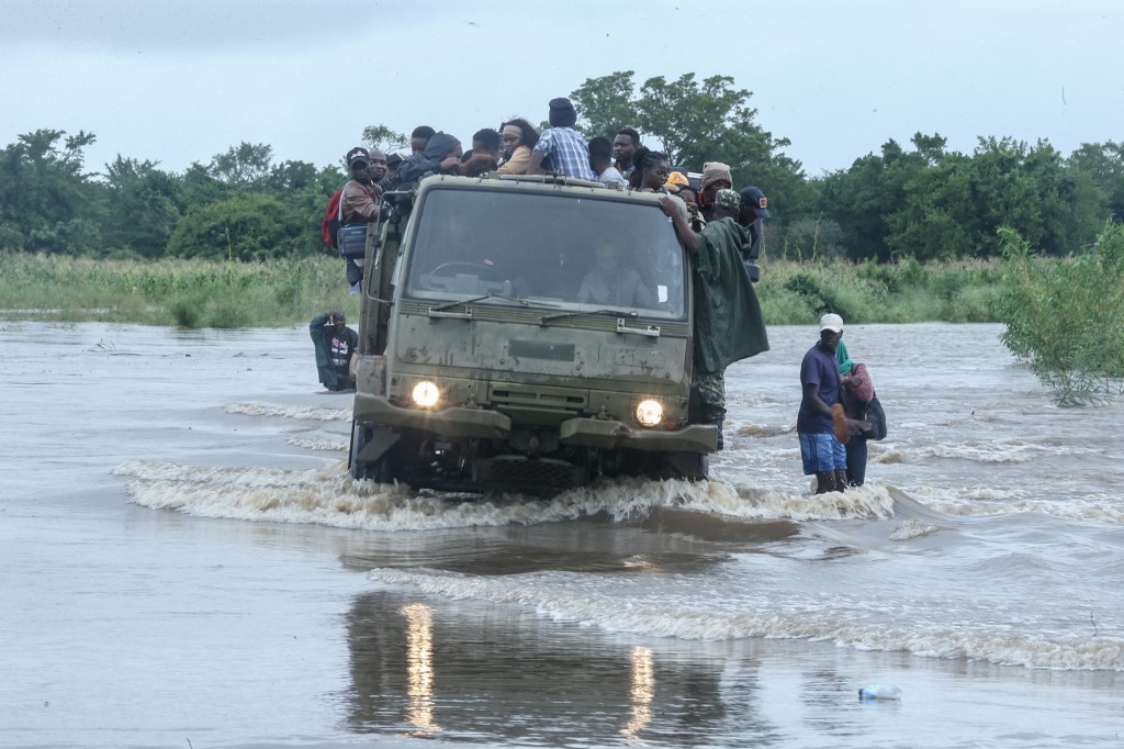 Residents sit on a Mozambique military truck transporting them across floodwater that blocked a road in the Boane district on January 16, 2026. Mozambique has experienced weeks of heavy rains and residents of low-lying areas near the capital, Maputo, were urged to evacuate to higher ground on January 16, 2026. (Photo by Amilton Neves / AFP)