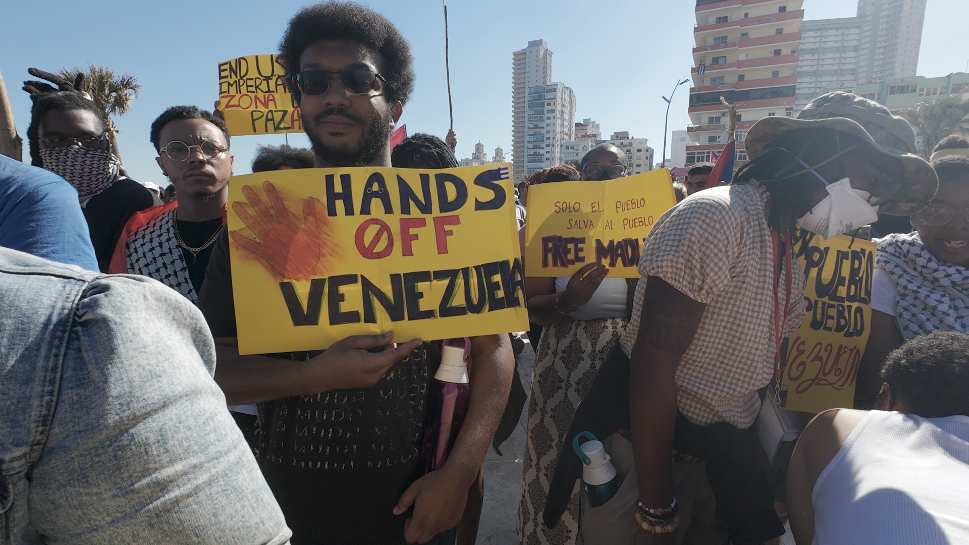 A protest unfolds in Havana, where people hold signs that read, "Hands off Cuba"