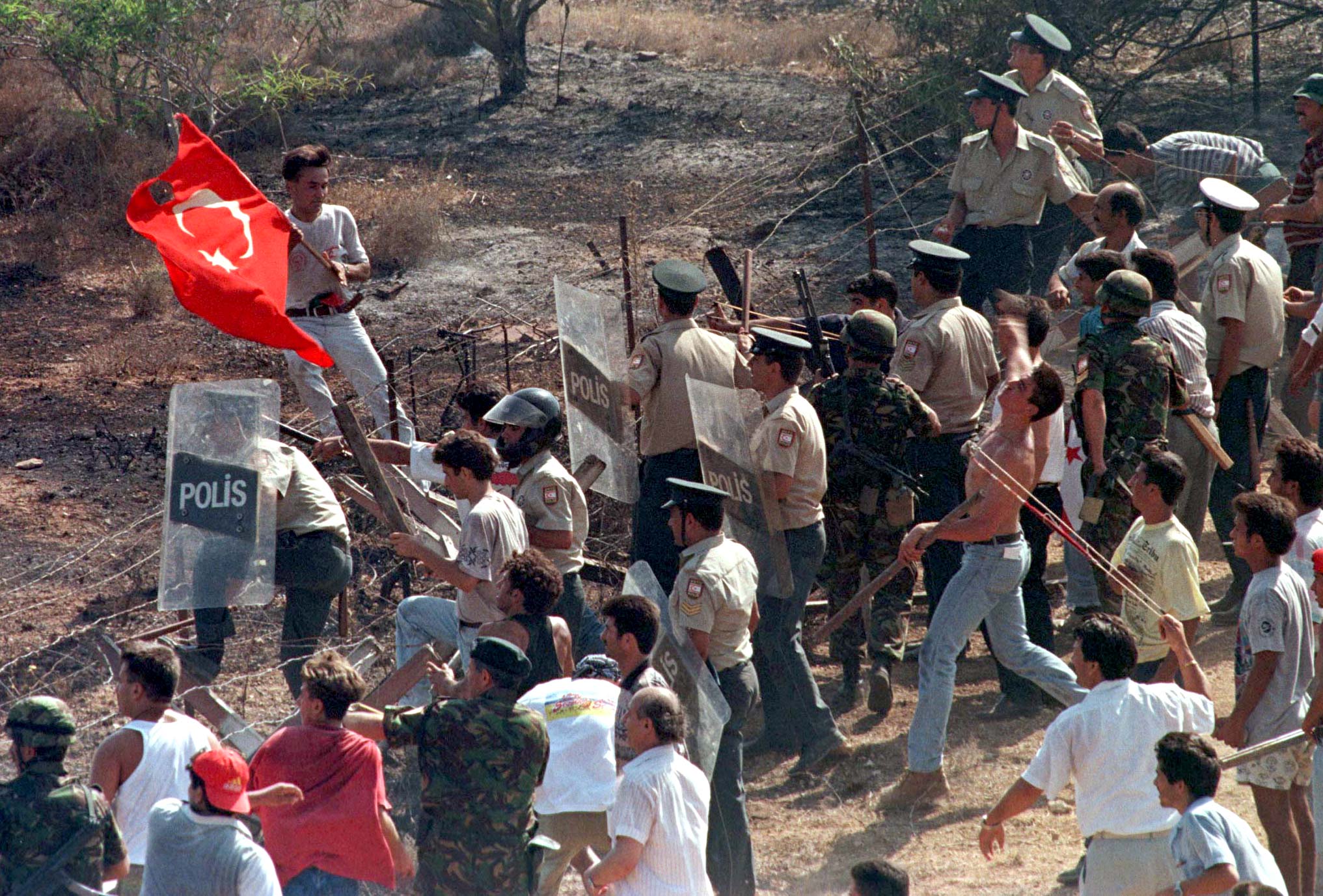 Turkish Cypriots, using slings, hurl stones against Greek Cypriots entering in the buffer zone in Derinya while the Turkish Cypriot police using shields try to stop them during a clash between Turkish and Greek Cypriots, August 11. A Greek Cypriot man was killed and 41 people wounded in clashes with Turkish Cypriots across the ceasefire line that has divided the island since Turkey invaded the north in 1974.
