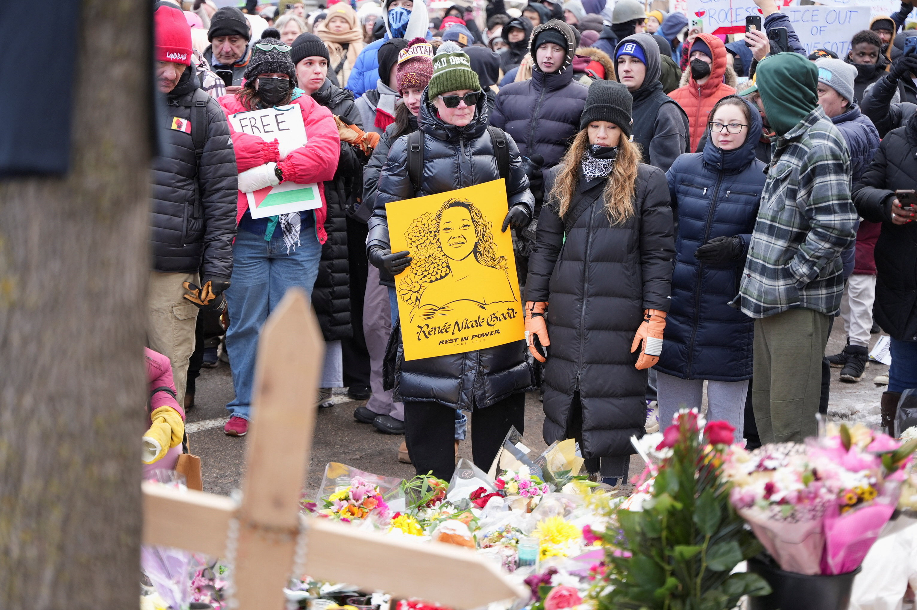 Protesters hold up signs in memory of Renee Nicole Good.