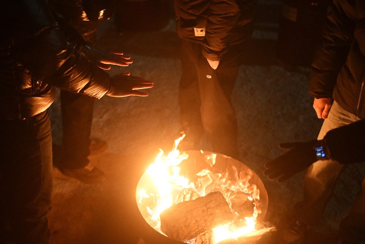 Local residents gather around a bonfire during an outdoor party to keep warm as many apartments remain without heating in Kyiv on January 18, 2026, amid the Russian invasion of Ukraine. Russian attacks have left Ukraine's energy grid teetering on the brink of collapse and have disrupted power and water supplies to millions over recent weeks