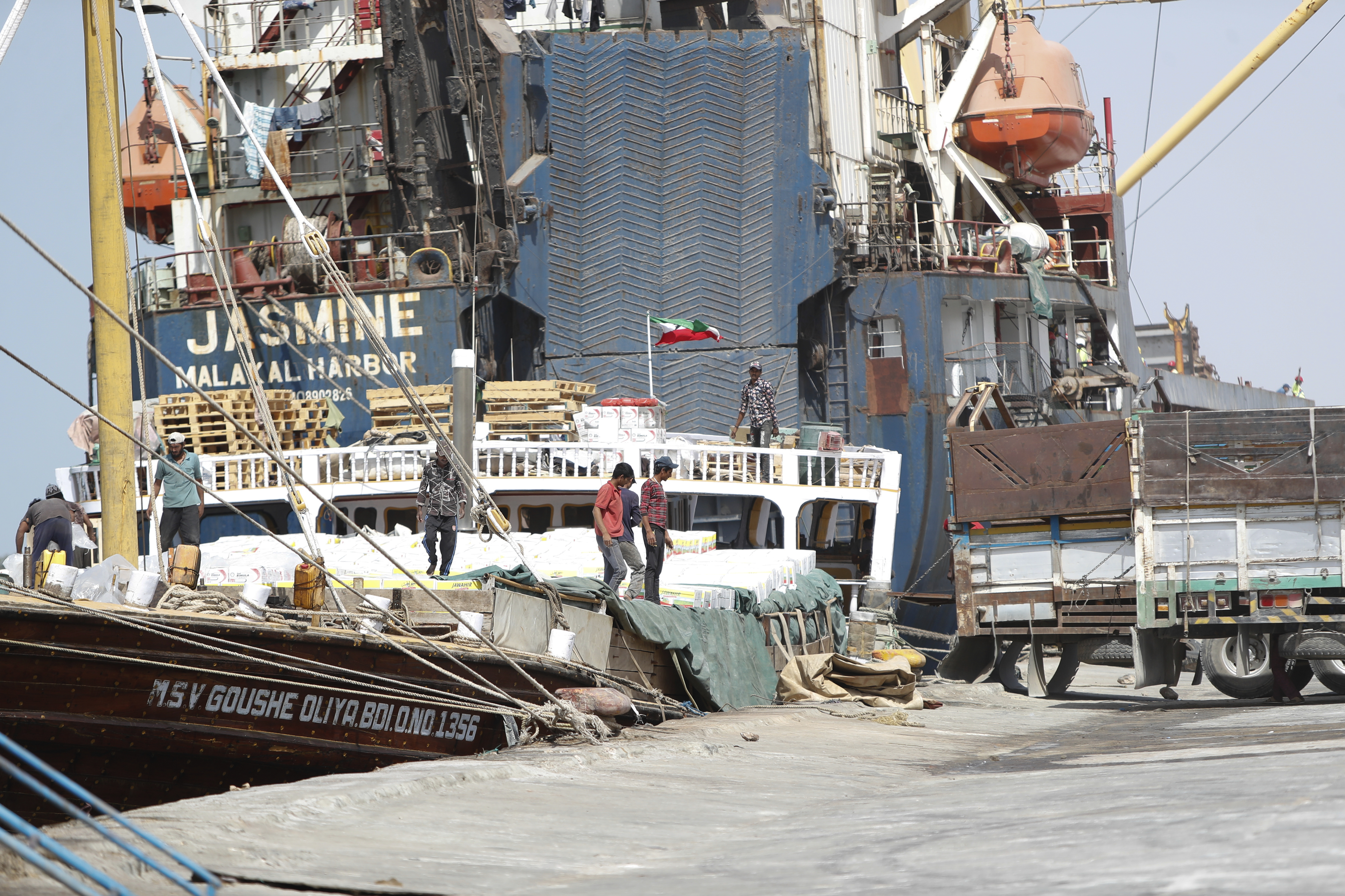 Workers offload goods from a docked ship at a seaport.