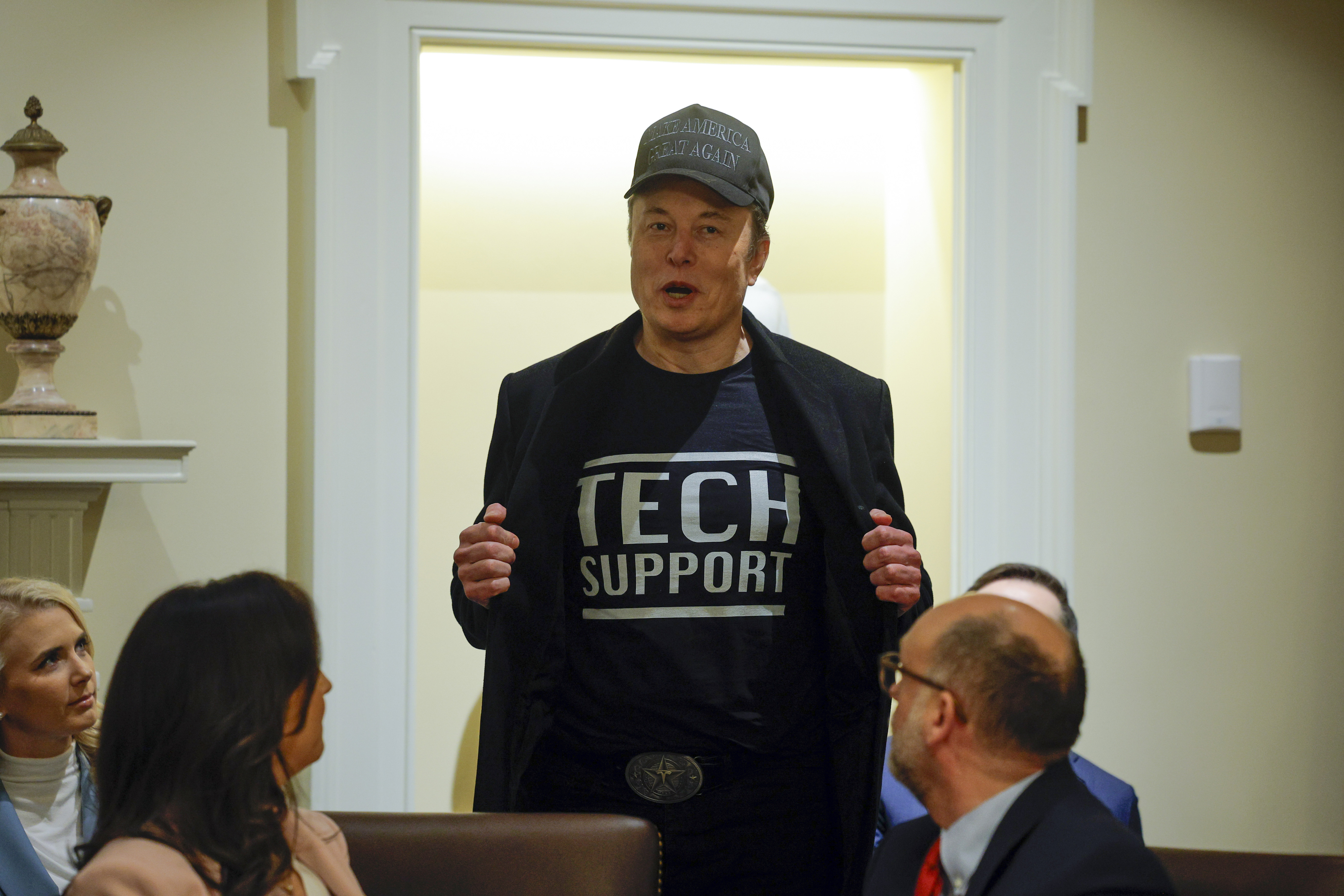 Elon Musk opens his blazer at a cabinet meeting to reveal "Tech Support" written on his shirt