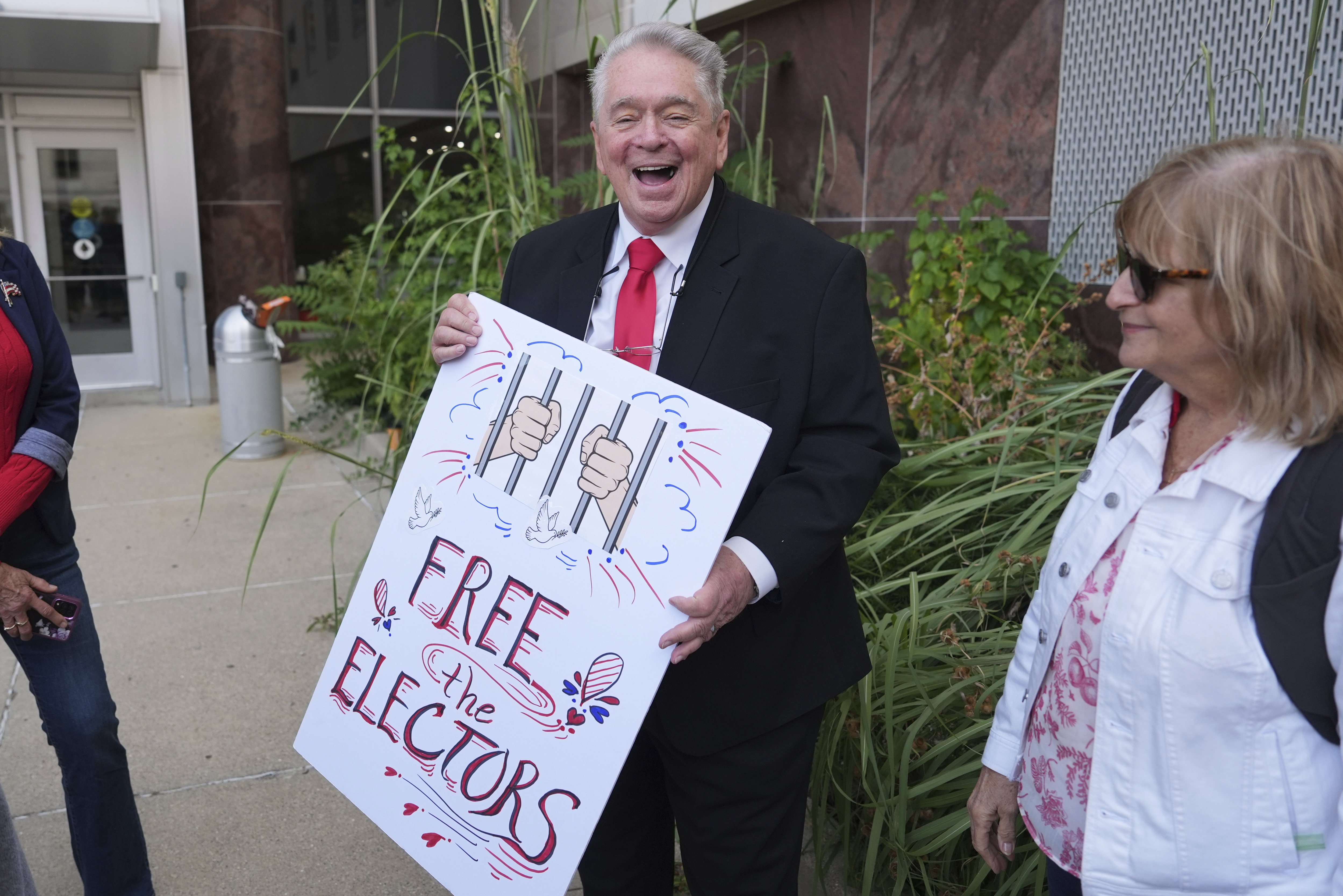 A man holds a poster that reads, "Free the electors."