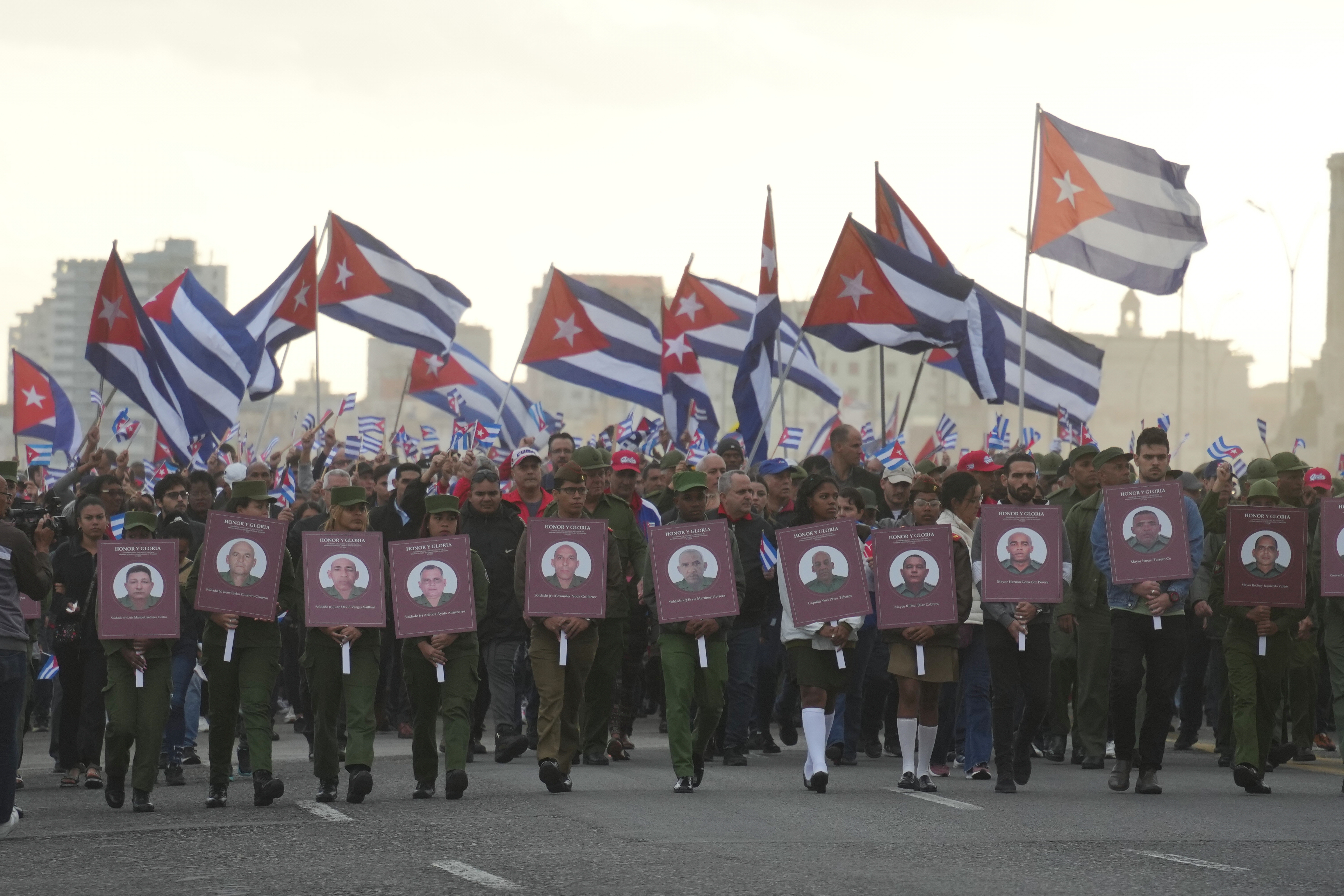 Soldiers carrying photos of Cuban officers killed during the U.S. operation in Venezuela that captured Venezuelan President Nicolas Maduro march the U.S. Embassy in Havana, Cuba, Friday, Jan. 16, 2026. (AP Photo/Ramon Espinosa)