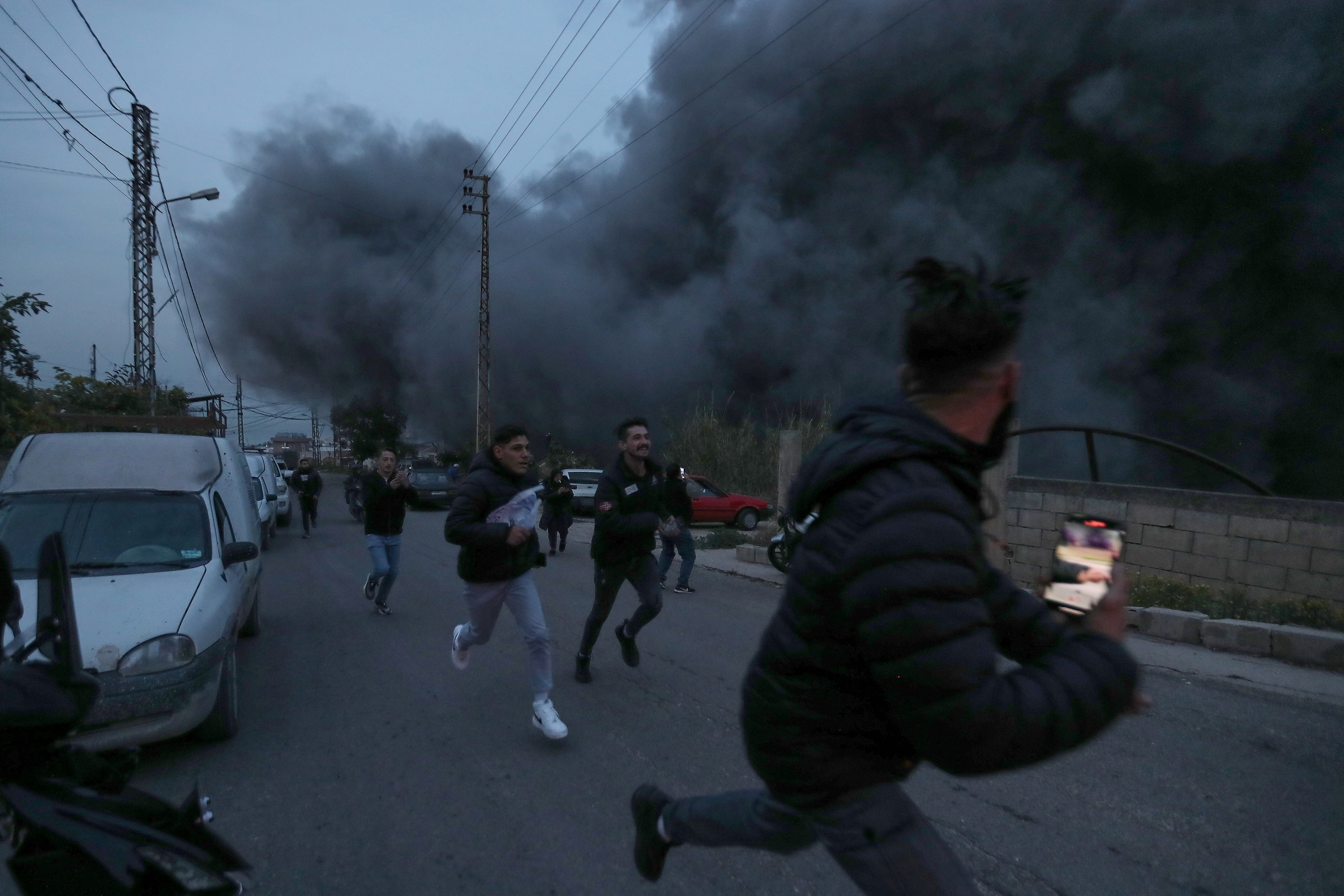 People run away as smoke rises after an Israeli airstrike in Qennarite village, south Lebanon, Wednesday, Jan. 21, 2026. (AP Photo/Mohammed Zaatari)