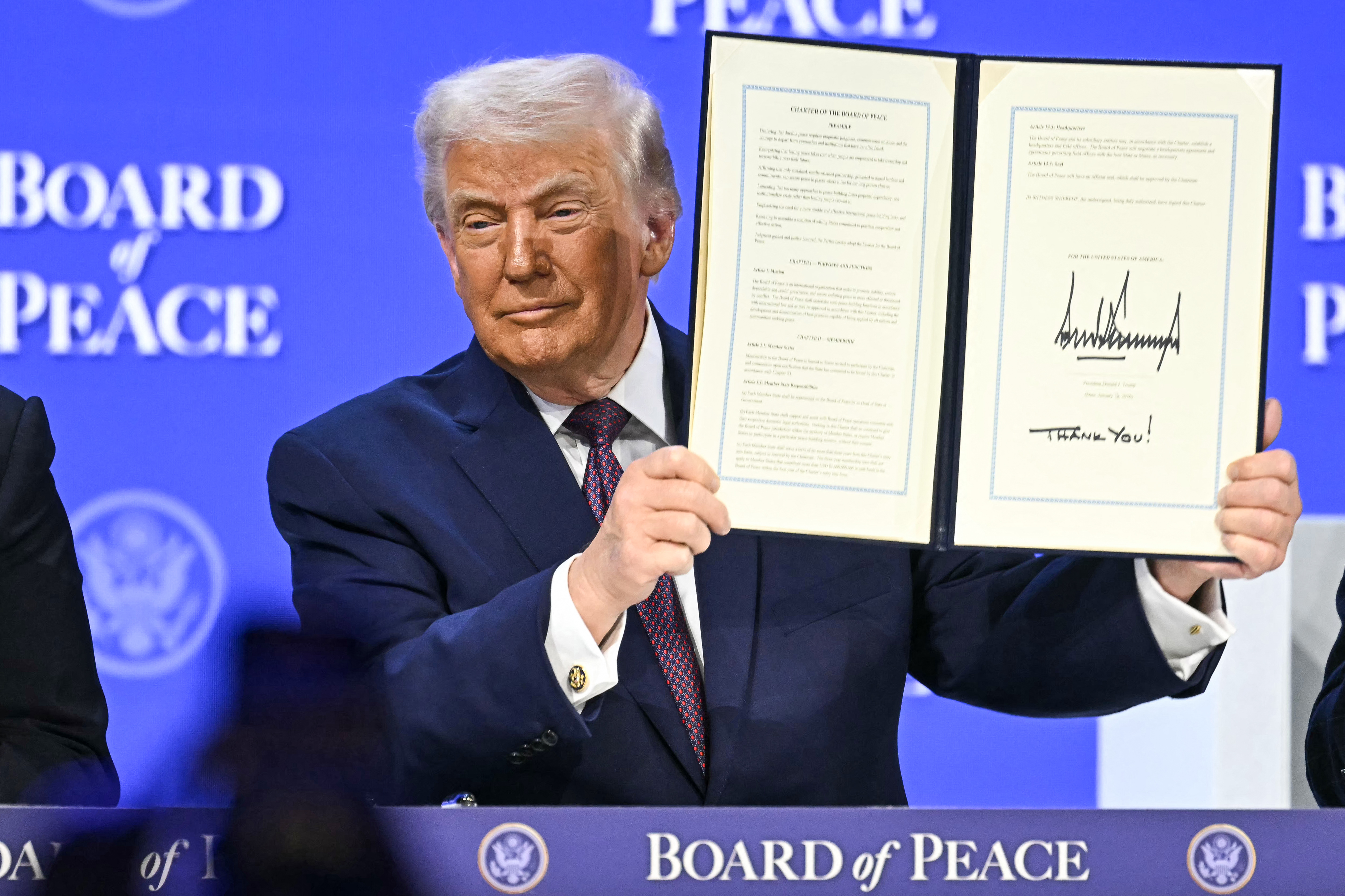 US President Donald Trump holds a signed founding charter at the Board of Peace meeting during the WEF annual meeting in Davos