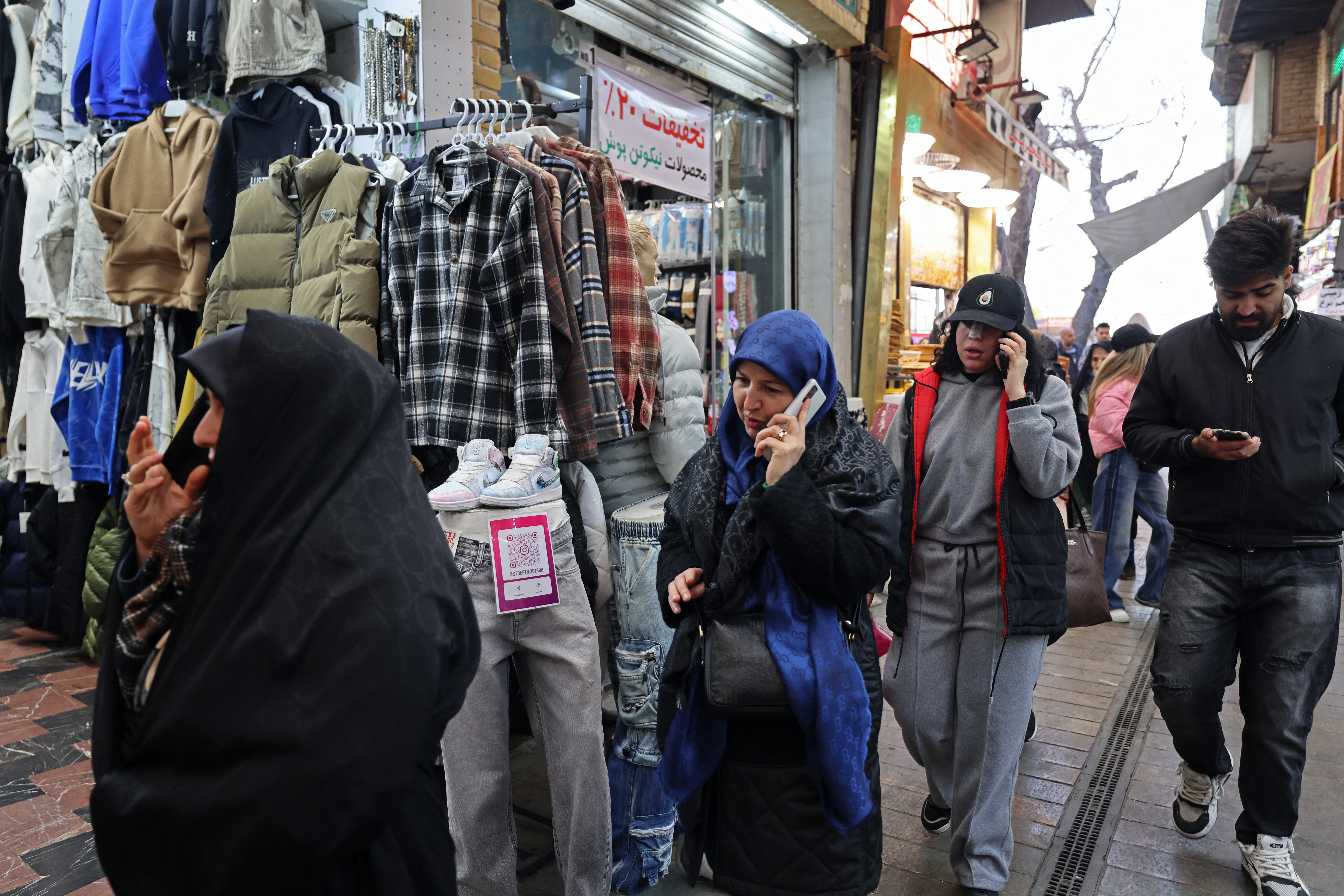 People use their mobile phones while walking through the Tajrish Bazaar in Tehran on January 28, 2026.