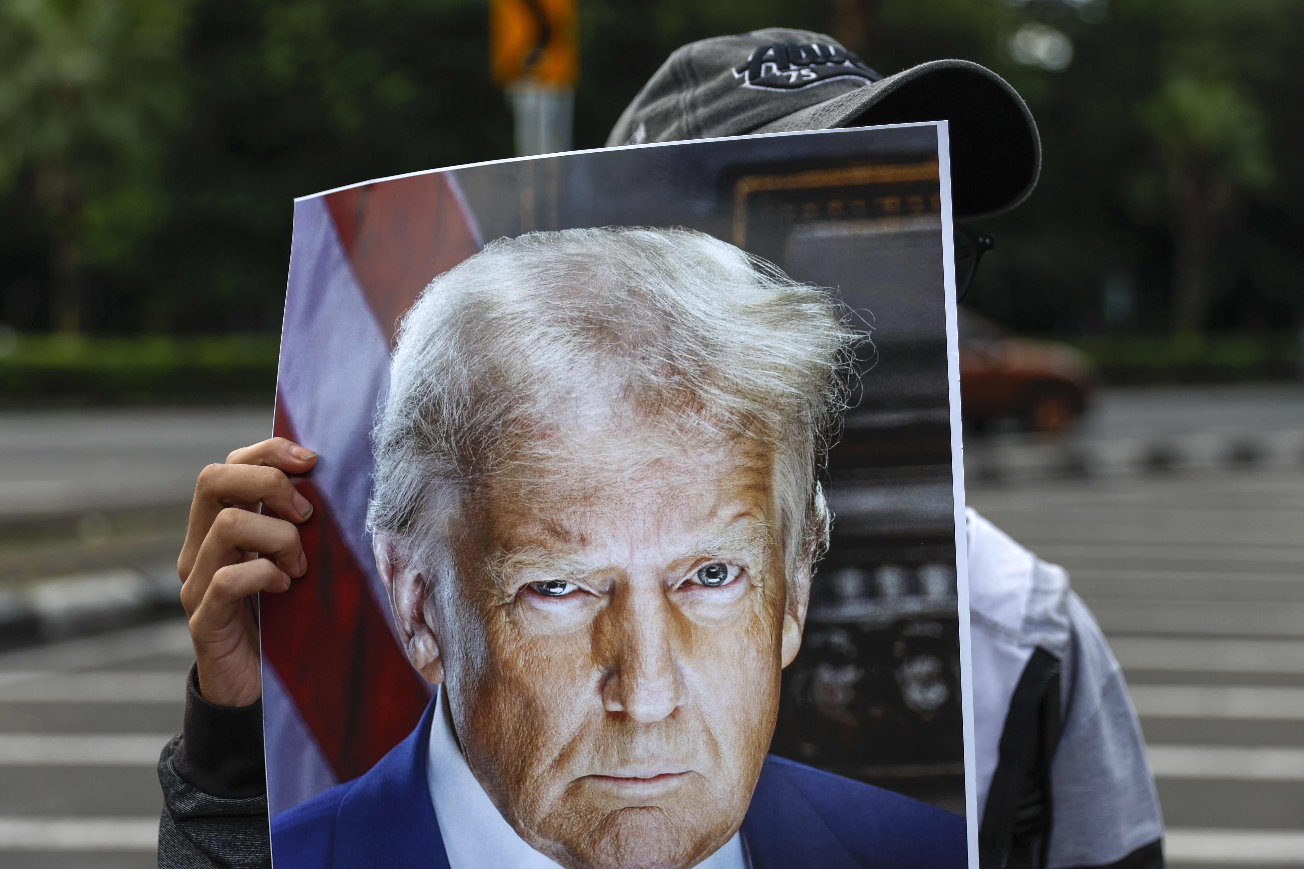 epa12682170 A protester holds a picture of US President Donald Trump during a protest outside the US Embassy in Jakarta, Indonesia, 26 January 2026. Protesters staged a rally against the US intervention in global politics that violates the world order and principles of international law. EPA/MAST IRHAM