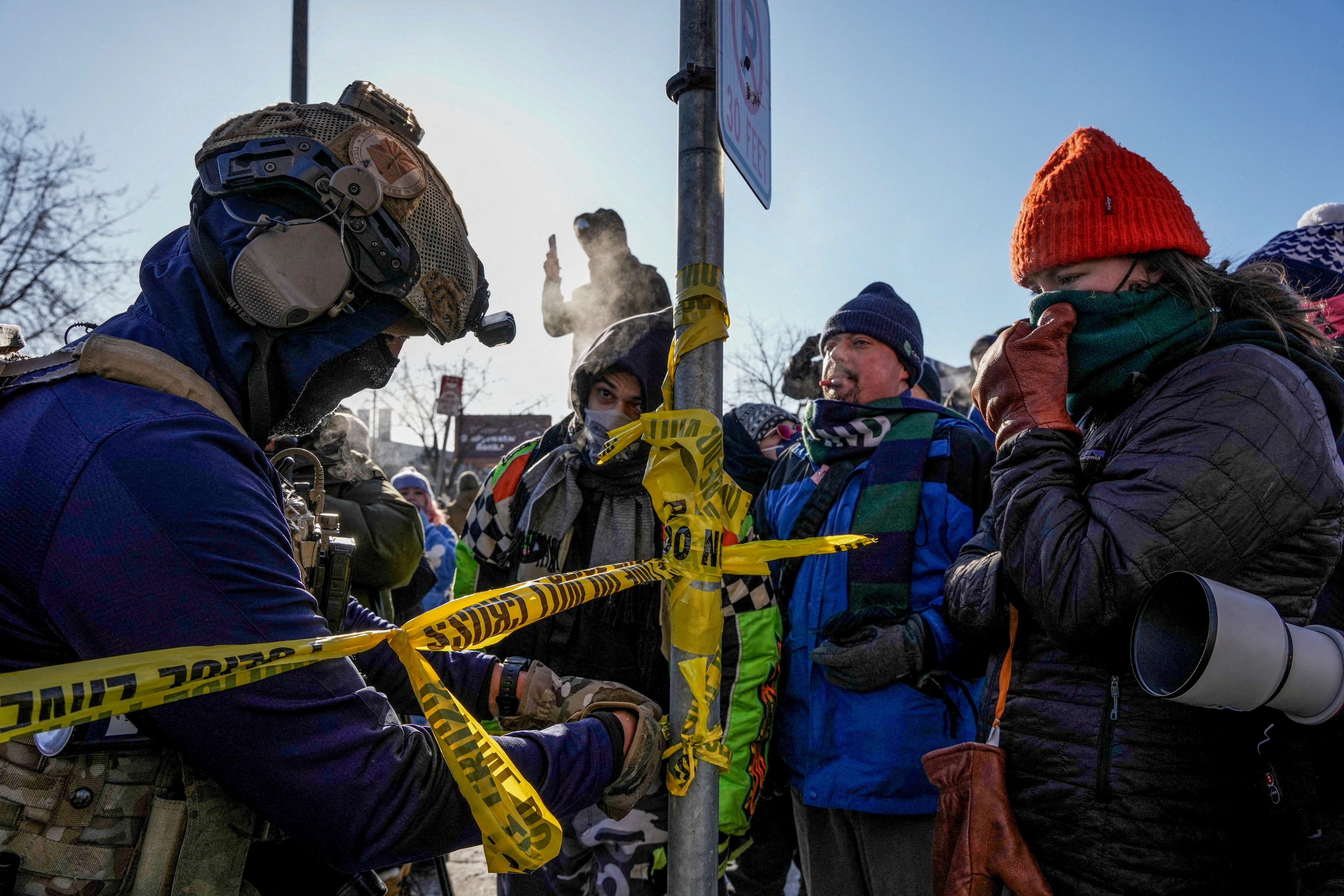 A federal agent cordons off the area as people gather at the scene of a shooting involving federal immigration agents in Minneapolis, Minnesota, U.S., January 24, 2026. REUTERS/Tim Evans REFILE - QUALITY REPEAT