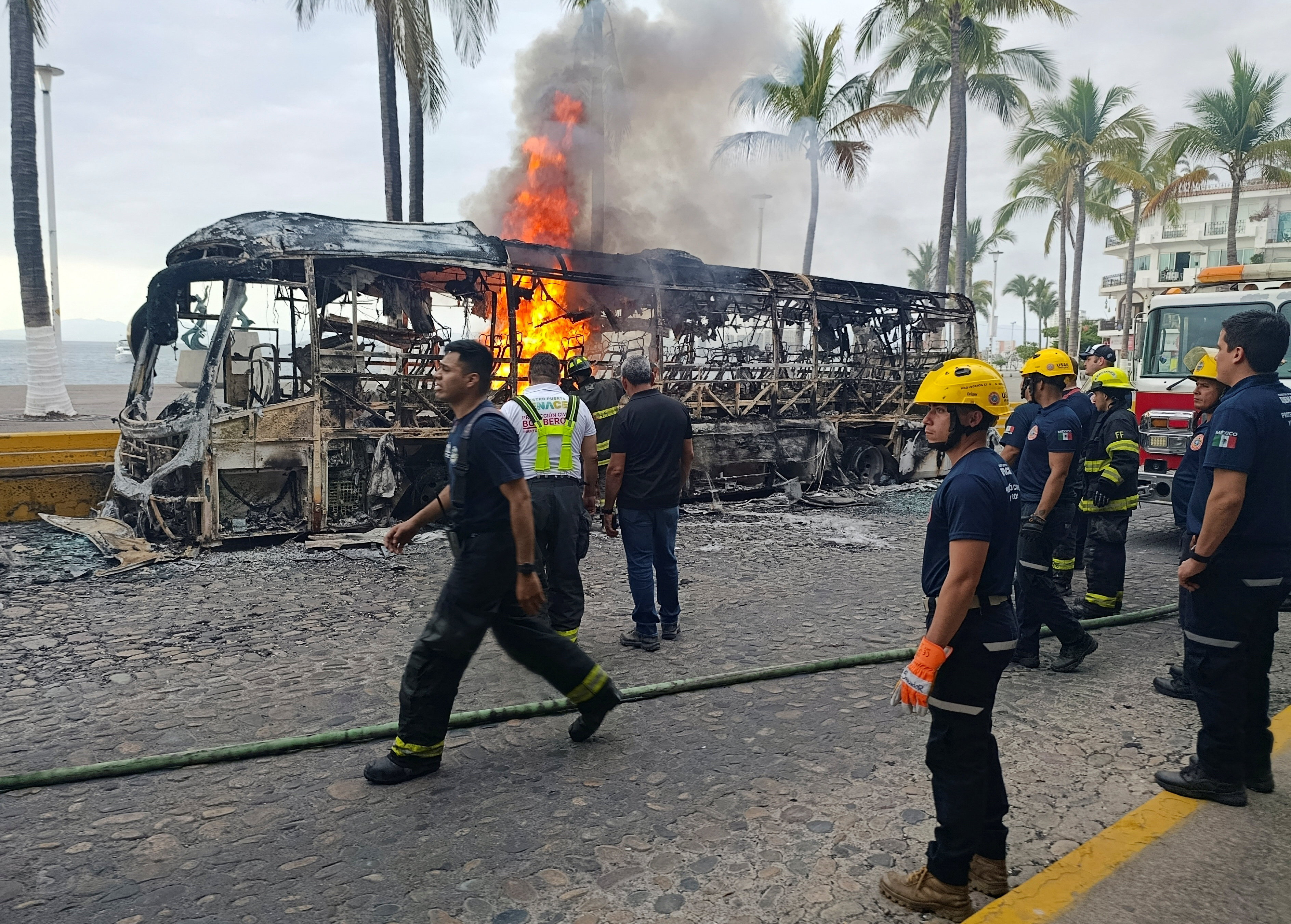 Firefighters work to extinguish flames from buses set on fire by members of organized crime following a military operation in which Mexican officials said cartel boss Nemesio Oseguera, "El Mencho," was killed, at a tourist area, in Puerto Vallarta, Mexico,