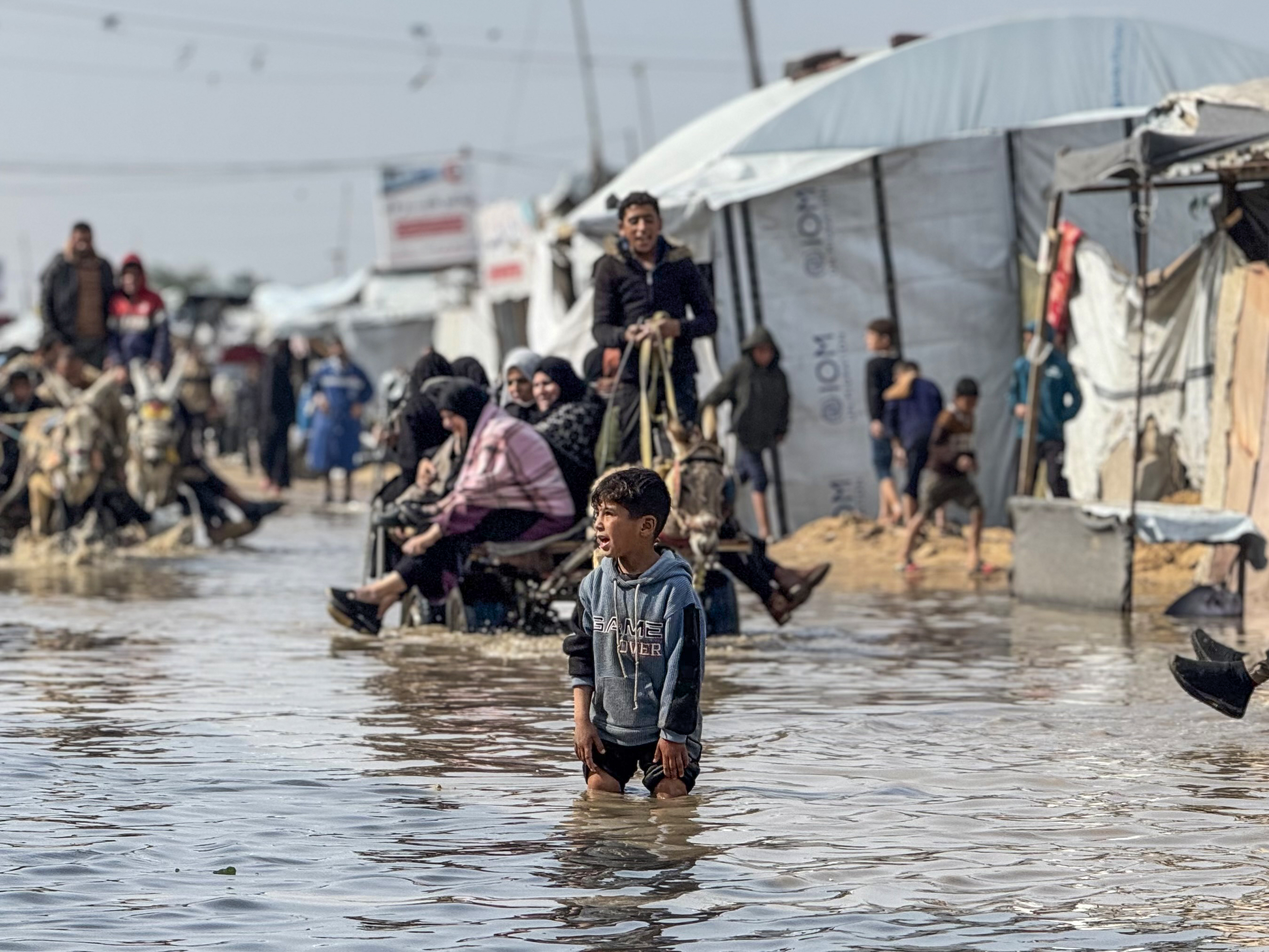 Palestinians navigate a flooded street.