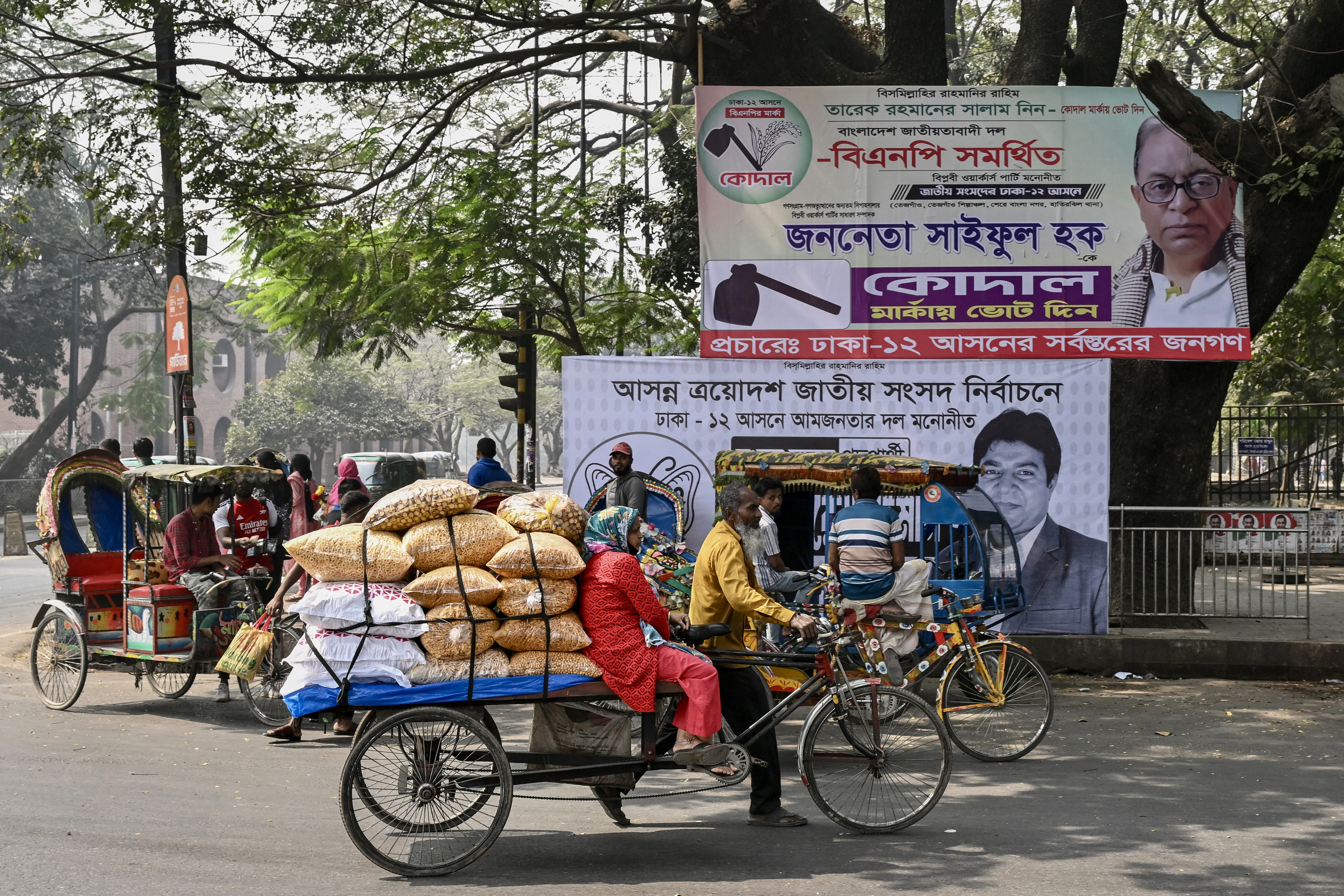 A rickshaw puller passes in front of campaign posters of parliamentary candidates displayed along a street in Dhaka on February 11, 2026 on the eve of Bangladesh's general elections.