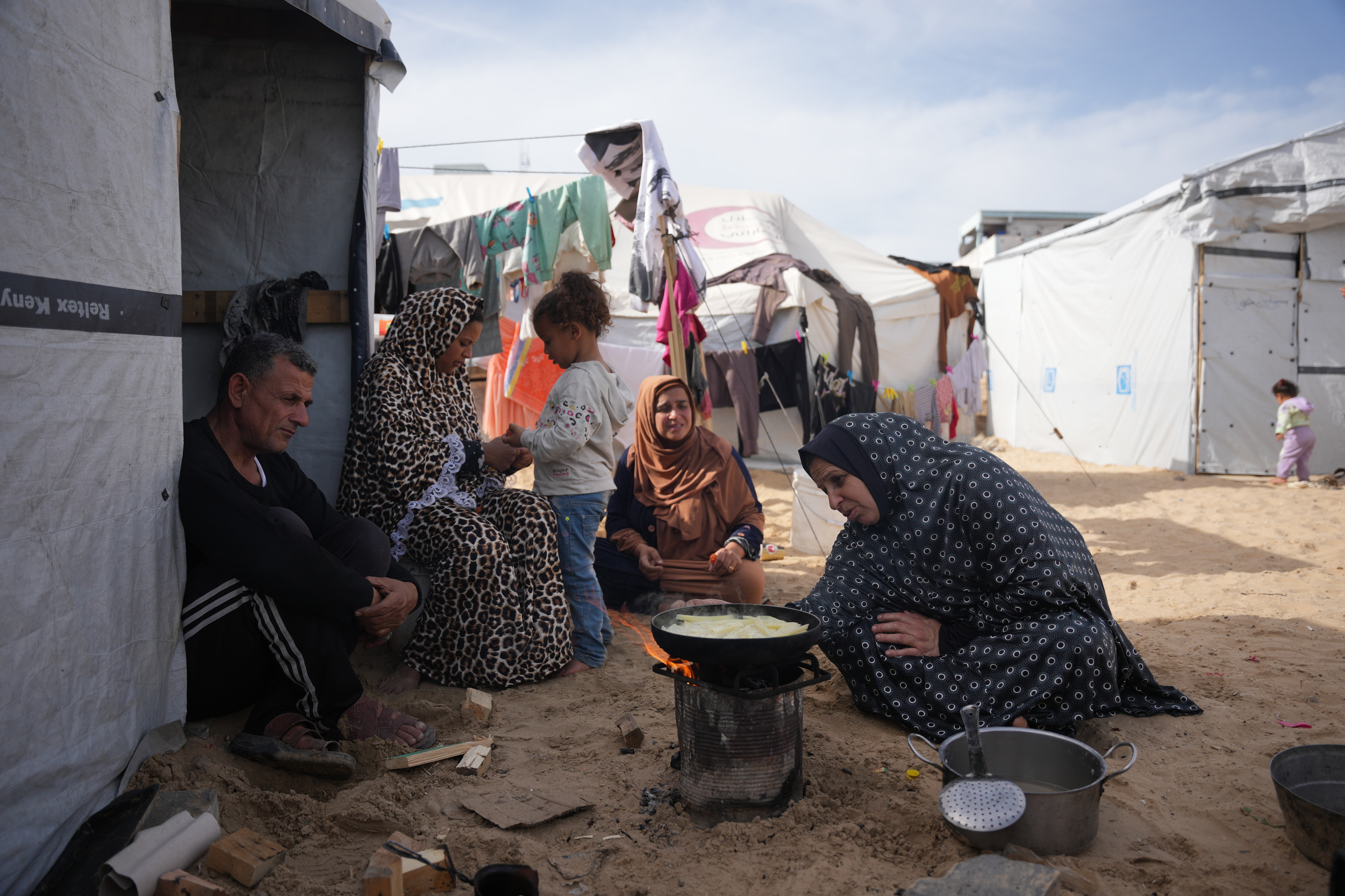 Siham Omran, 54, recently returned from Egypt after completing medical treatment, cooks food over a fire beside her tent in Khan Younis, in the southern Gaza Strip, Saturday, Feb. 7, 2026. (AP Photo/Abdel Kareem Hana)