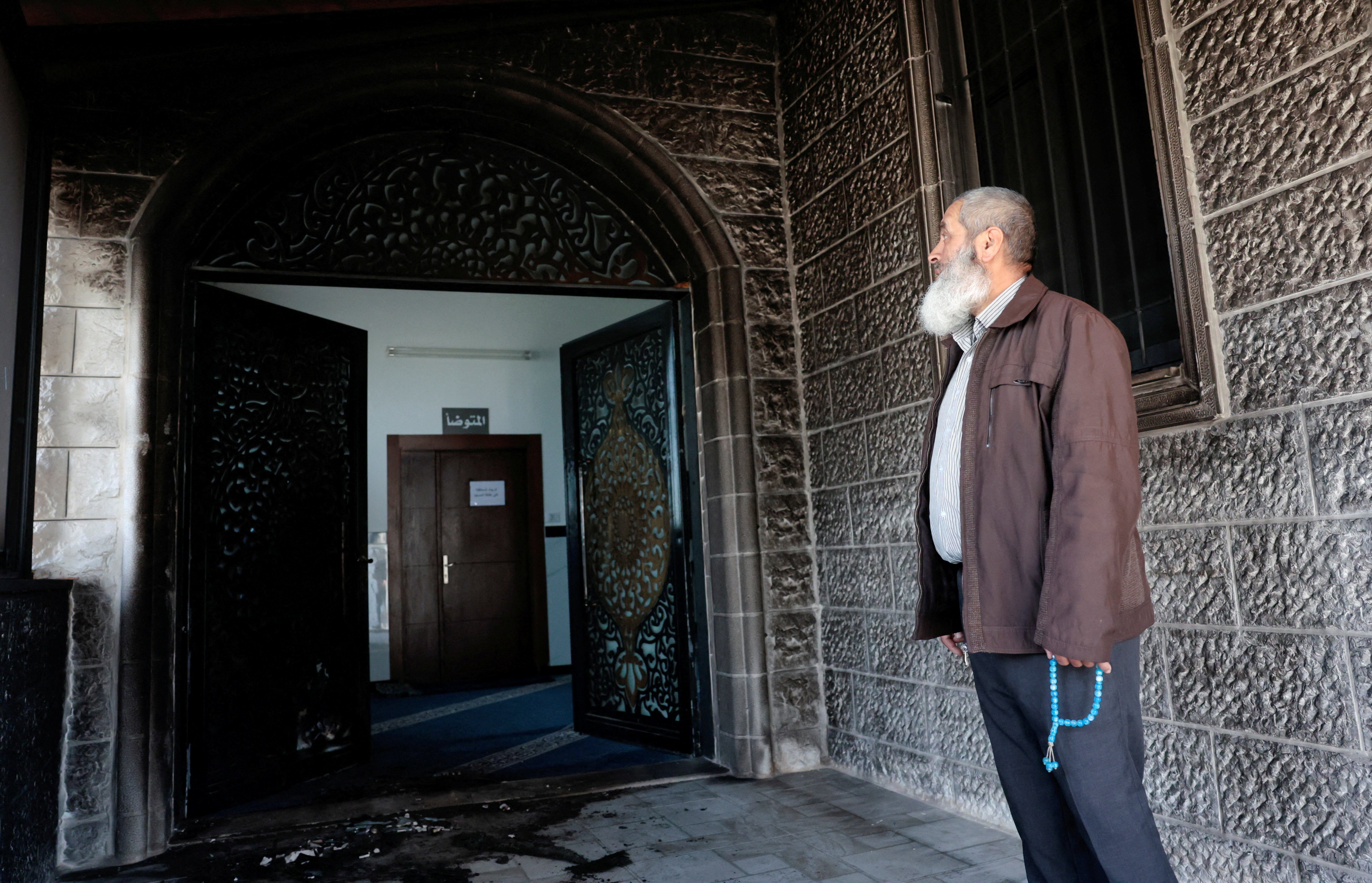 A Palestinian man, holding Misbaha prayer beads, inspects the debris at a mosque, which Palestinians say was damaged by Israeli settlers, in West Bank village of Surra, near Nablus in the Israeli-occupied West Bank, February 23, 2026. REUTERS/Mohamad Torokman TPX IMAGES OF THE DAY