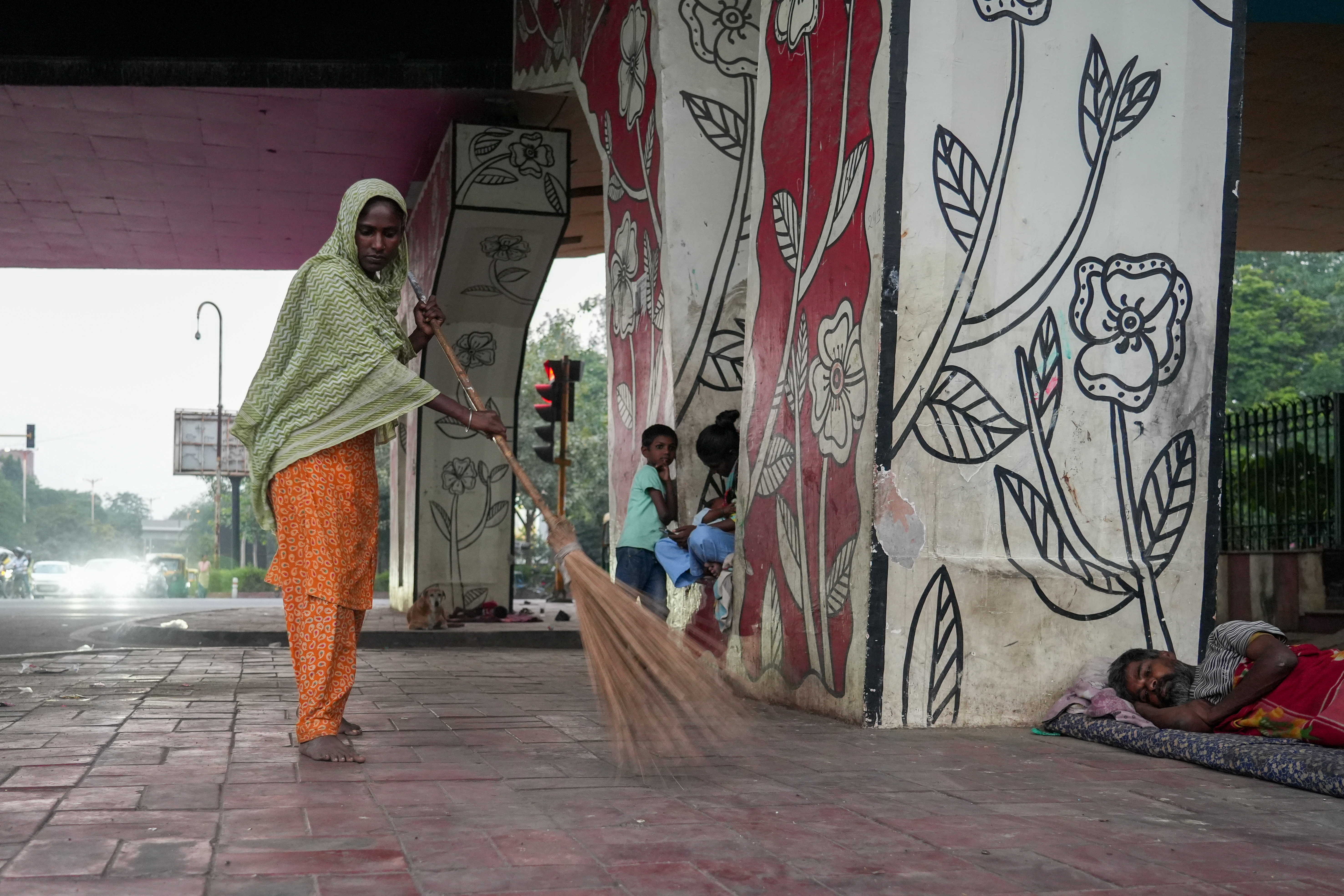 Every evening before sleep, Abida takes a coconut broomstick and sweeps the path where they will rest. She clears away dust and harmful insects, trying to make a small corner safe for her children. [Suhail Bhat/Al Jazeera]