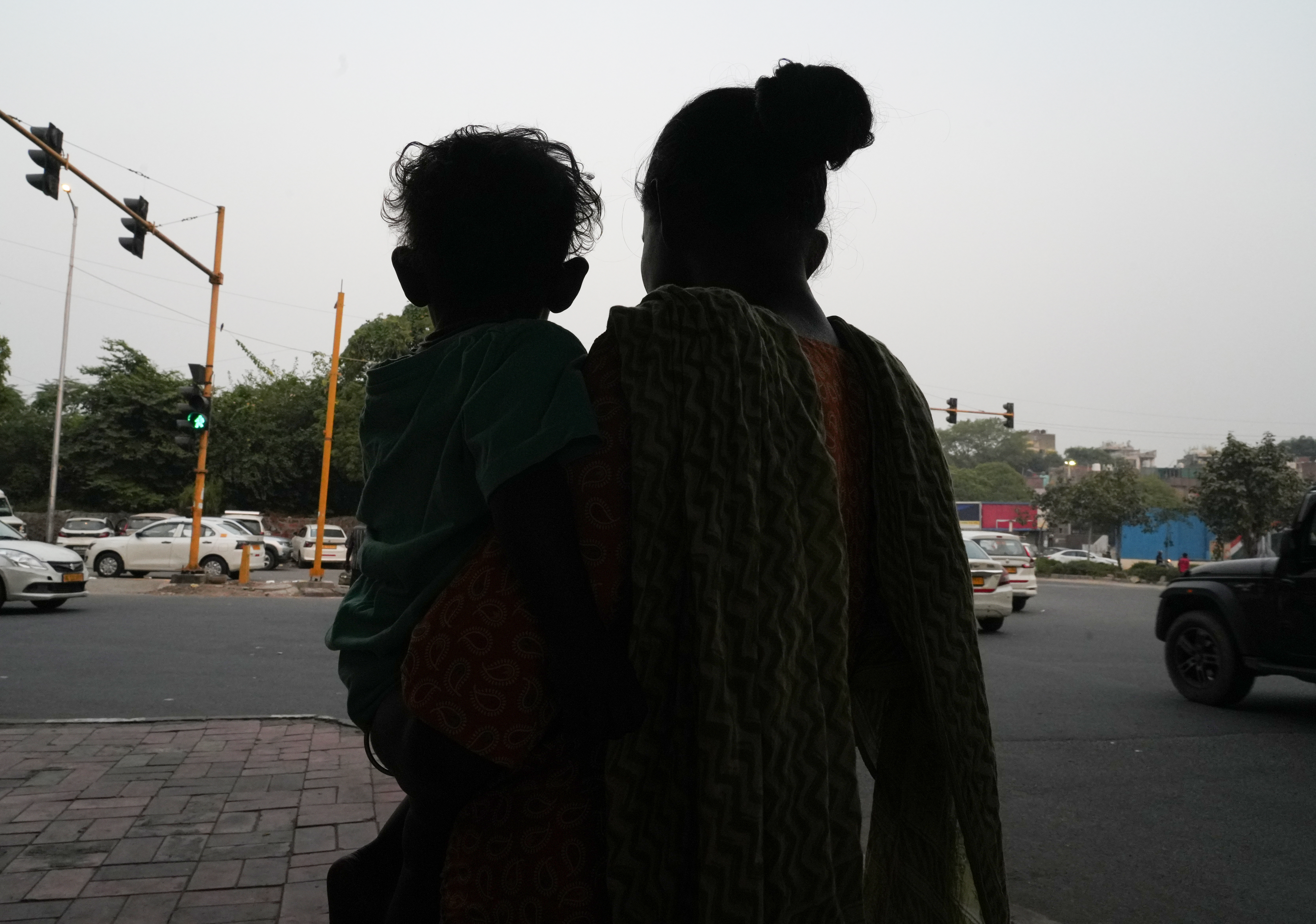 Abida carries her daughter at the red lights, seeking food or money from passersby who sometimes offer help. After her two other children were in an accident, she never lets Soni out of her sight, holding her close at all times. [Suhail Bhat/Al Jazeera]
