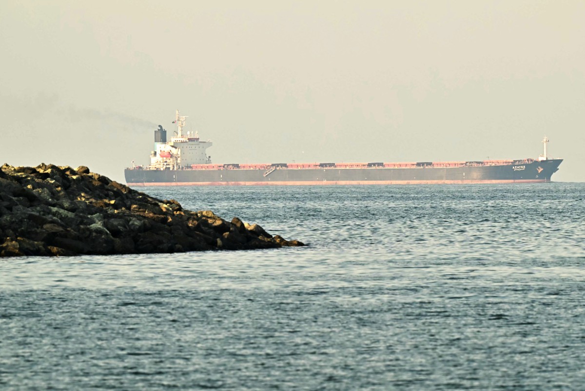 A cargo ship is pictured off a coast.